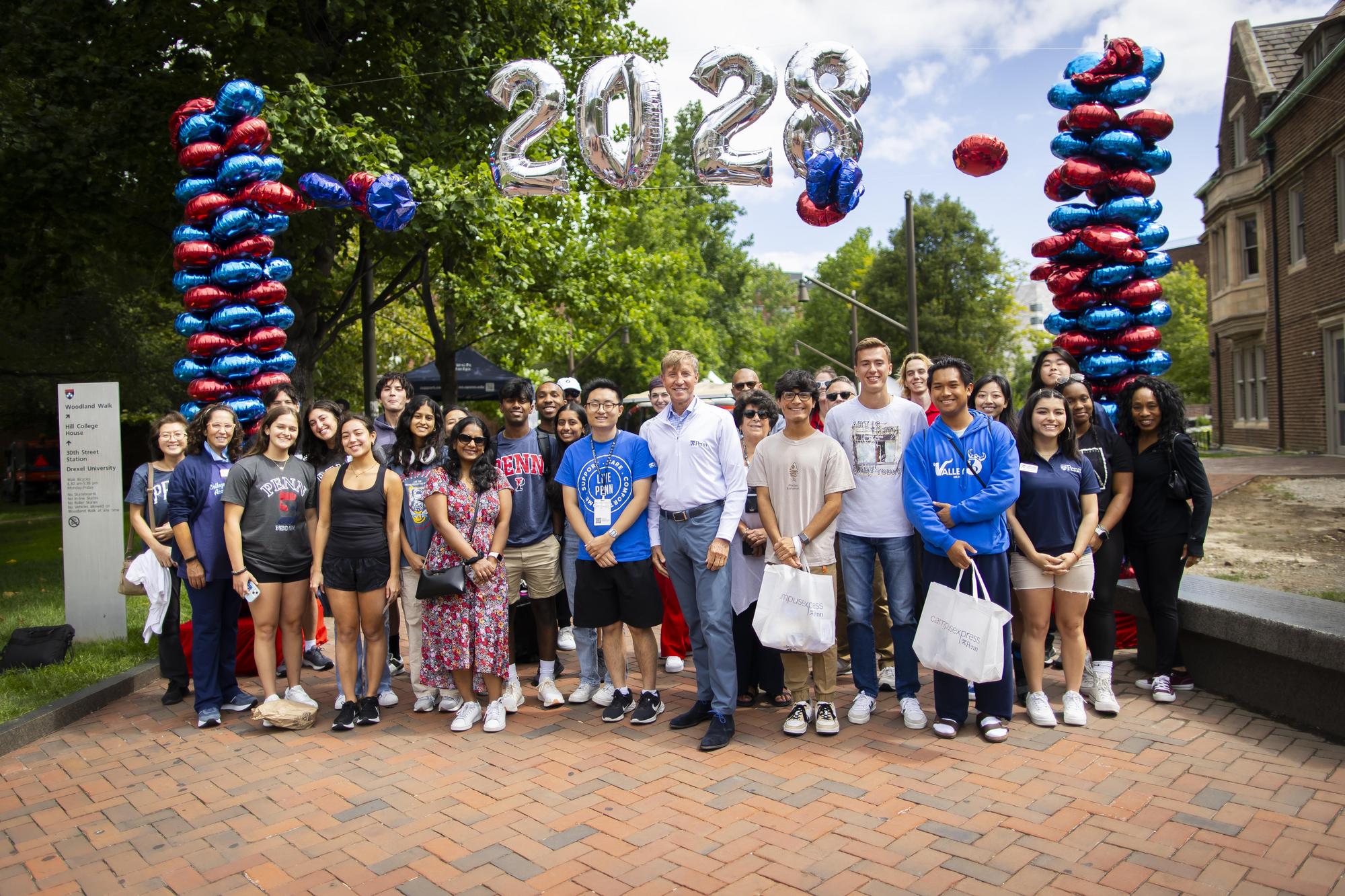 Penn President J. Larry Jameson stands with students and parents under the 2028 balloon arch on Penn’s campus during Move-In.