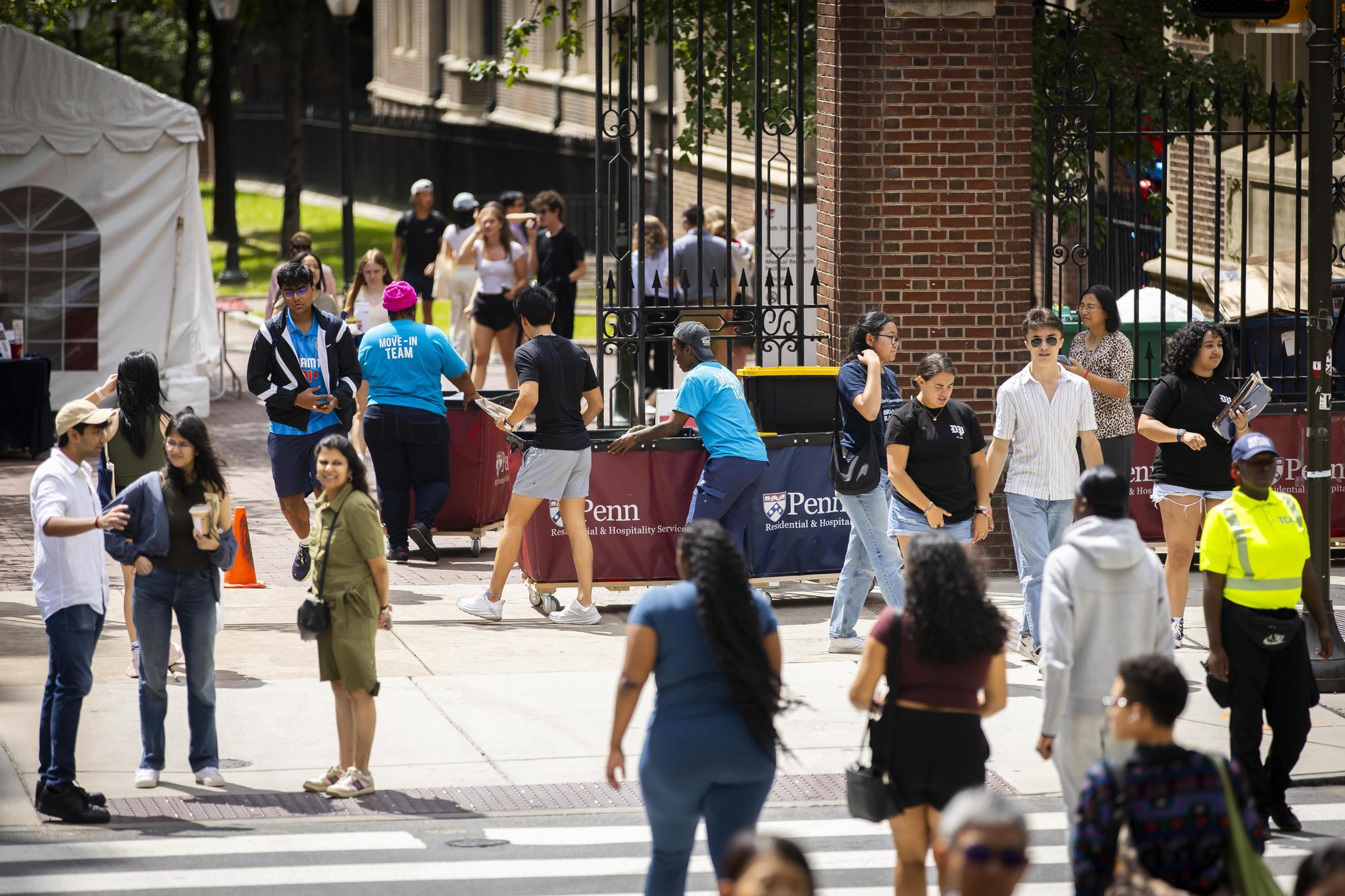 Students, parents, and Move-In coordinators outside with carts on Penn’s campus during Move-In.