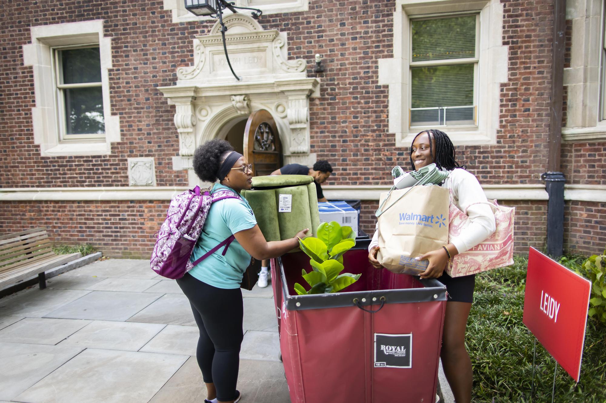 A Penn student and their parent unload items from a Move-In cart in front of a dorm on Move-In day.