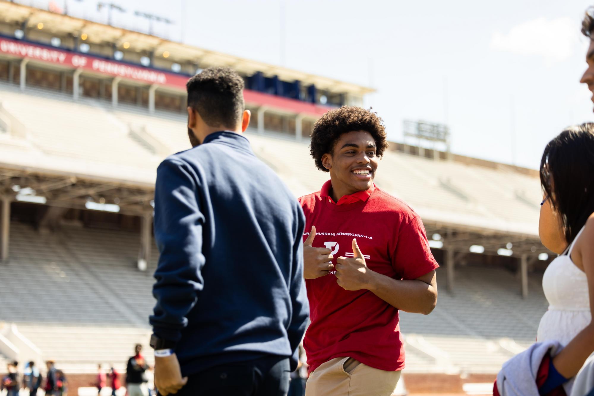 A new Penn student gives two thumbs up on Franklin Field on NSO weekend.