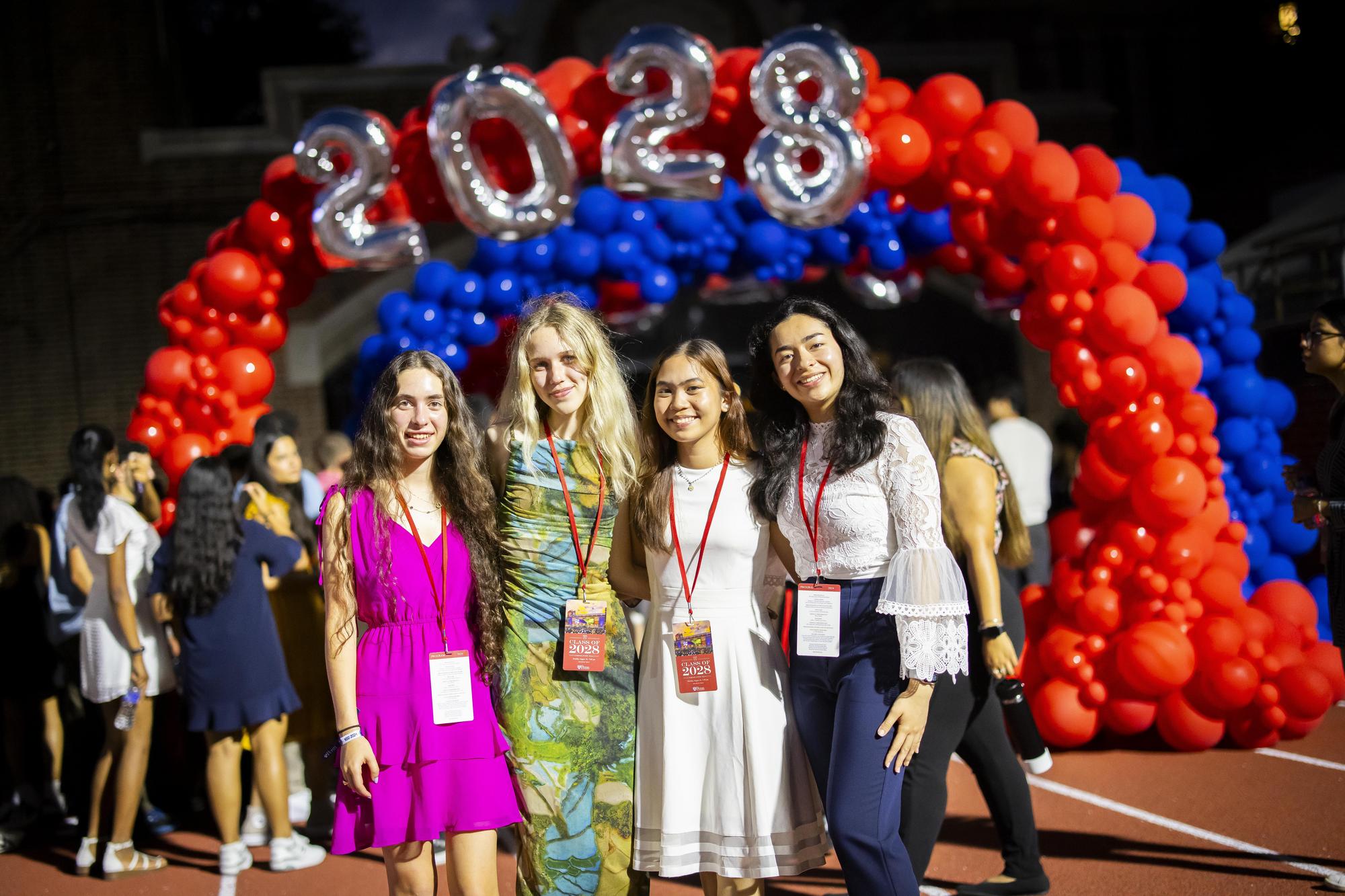 Four Penn students in the Class of 2028 in front of balloons at Penn’s Convocation.