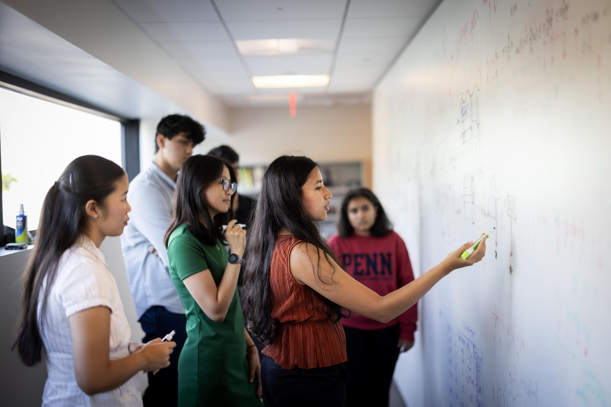 Students brainstorming around a whiteboard