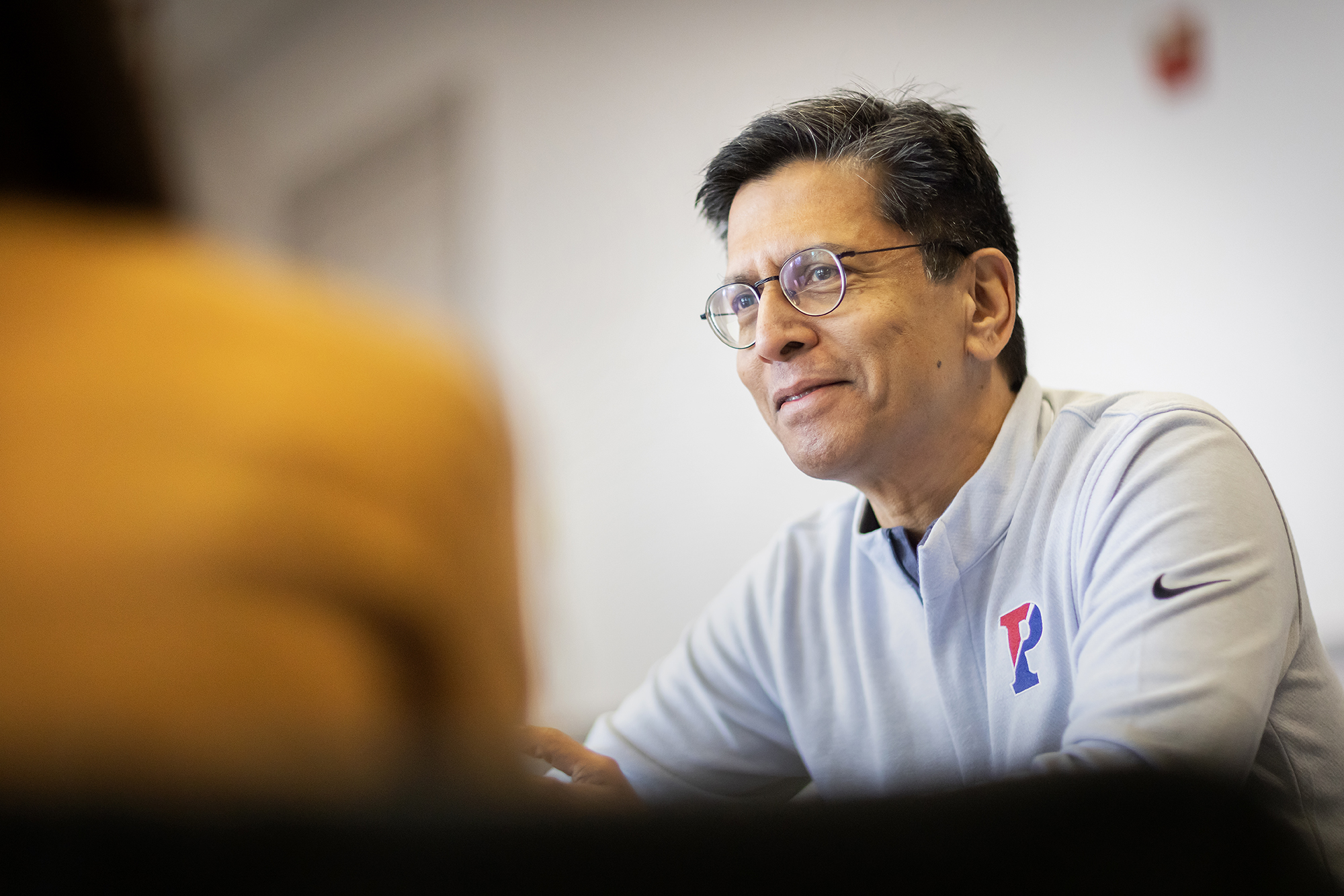 The board chair is seated at a table in conversation.