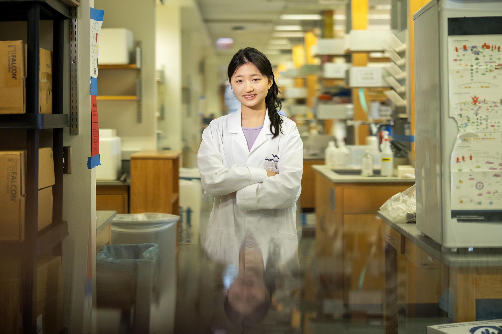 Jiayi Pang in a white coat, standing with her arms crossed in the lab 