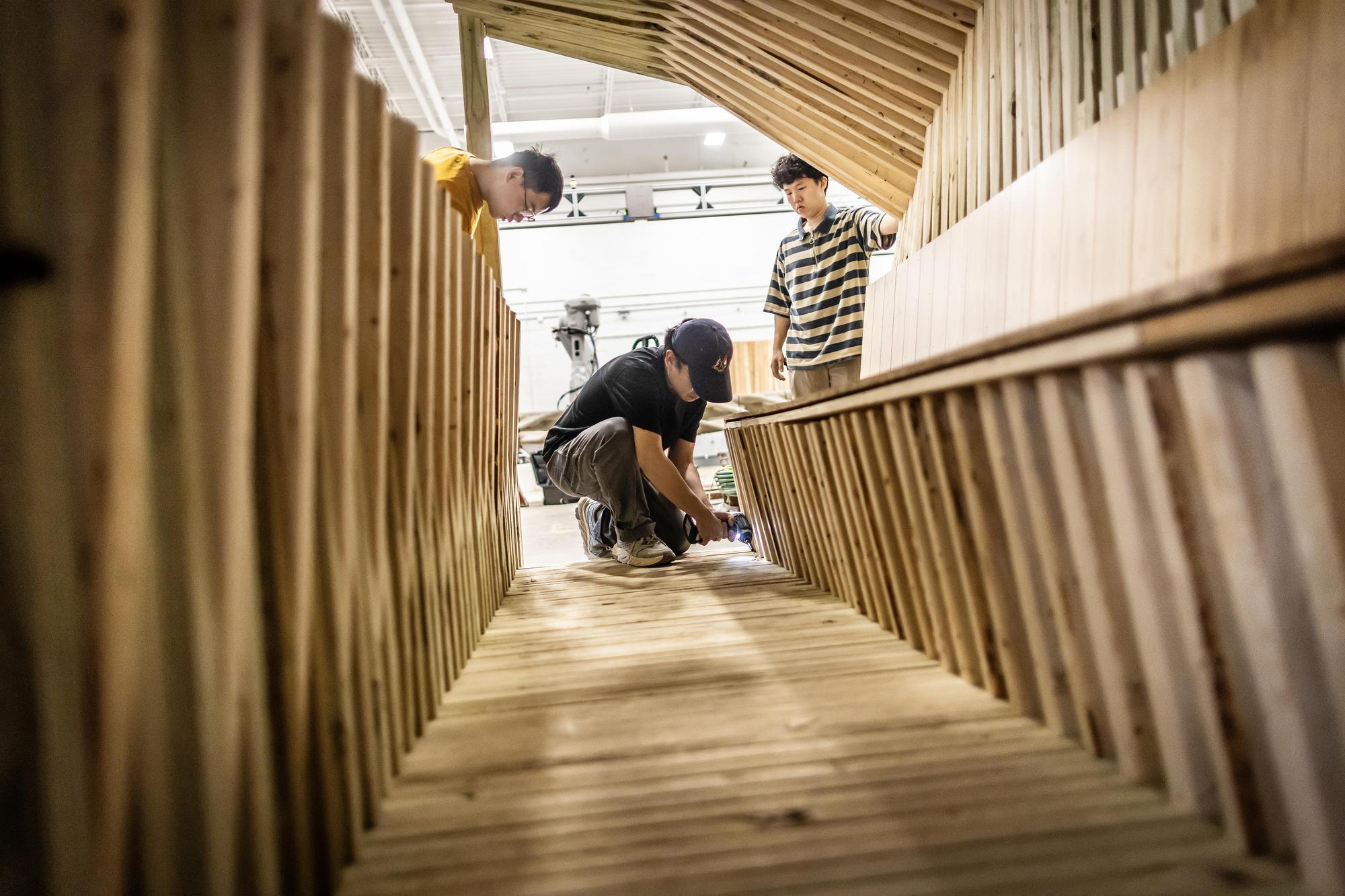 Three grad students building a wooden cooling shelter.