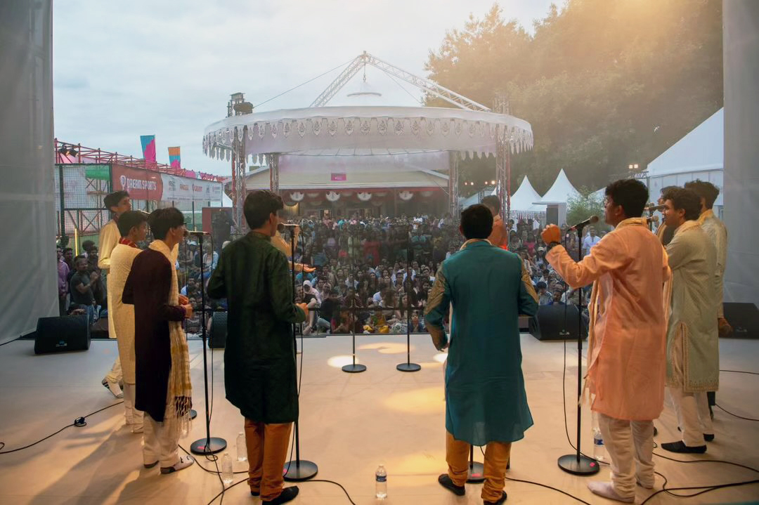 view from behind singers at microphones with a crowd in front of them