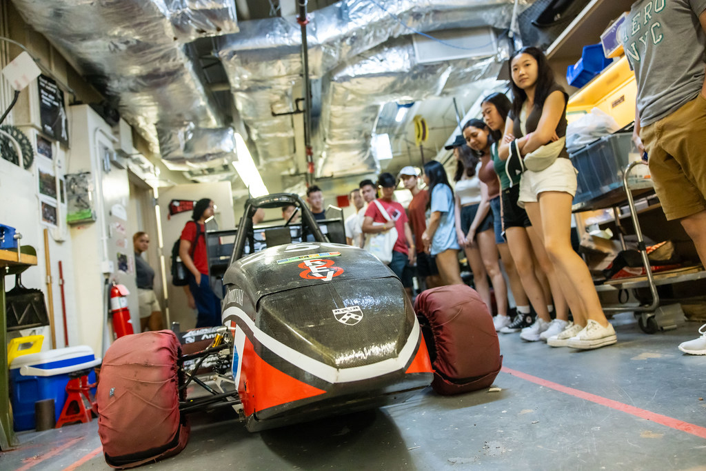 A small race car surrounded by students.