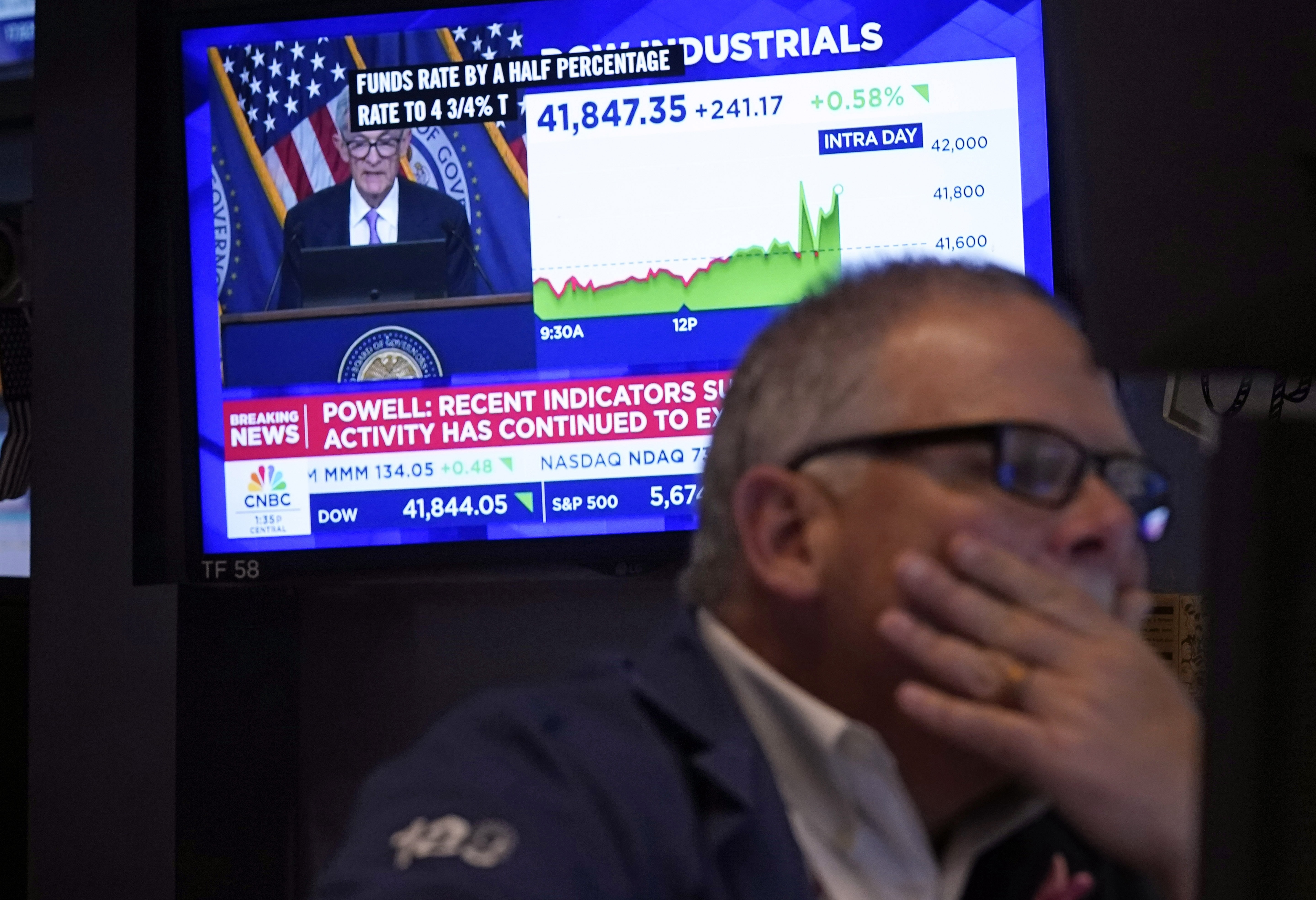 A stock trader is seen monitoring a screen showing Federal Reserve Chair Jerome Powell's announcement of a half-percentage point interest rate cut