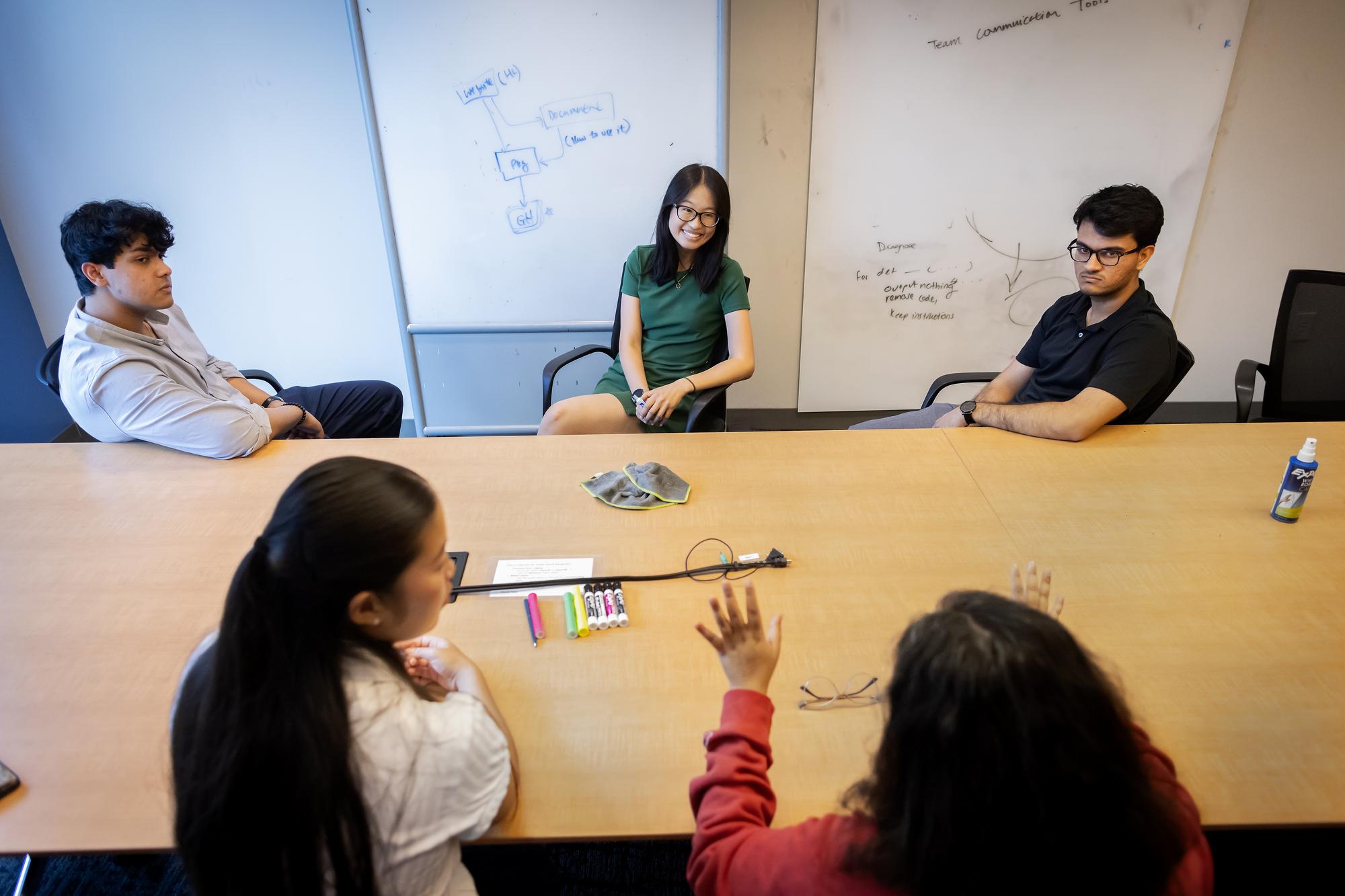 Group of students gather around a table to brainstorm.