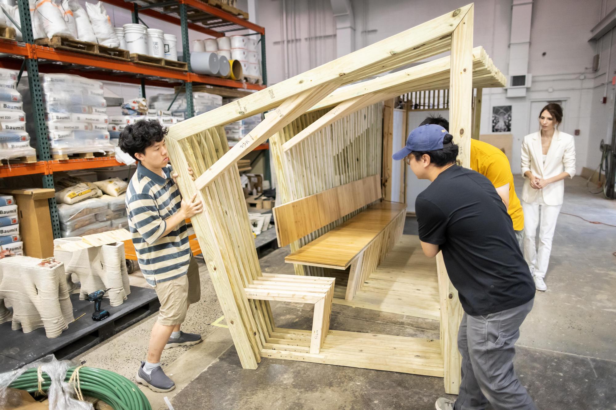 Four people working on a finished cooling shelter in a warehouse.