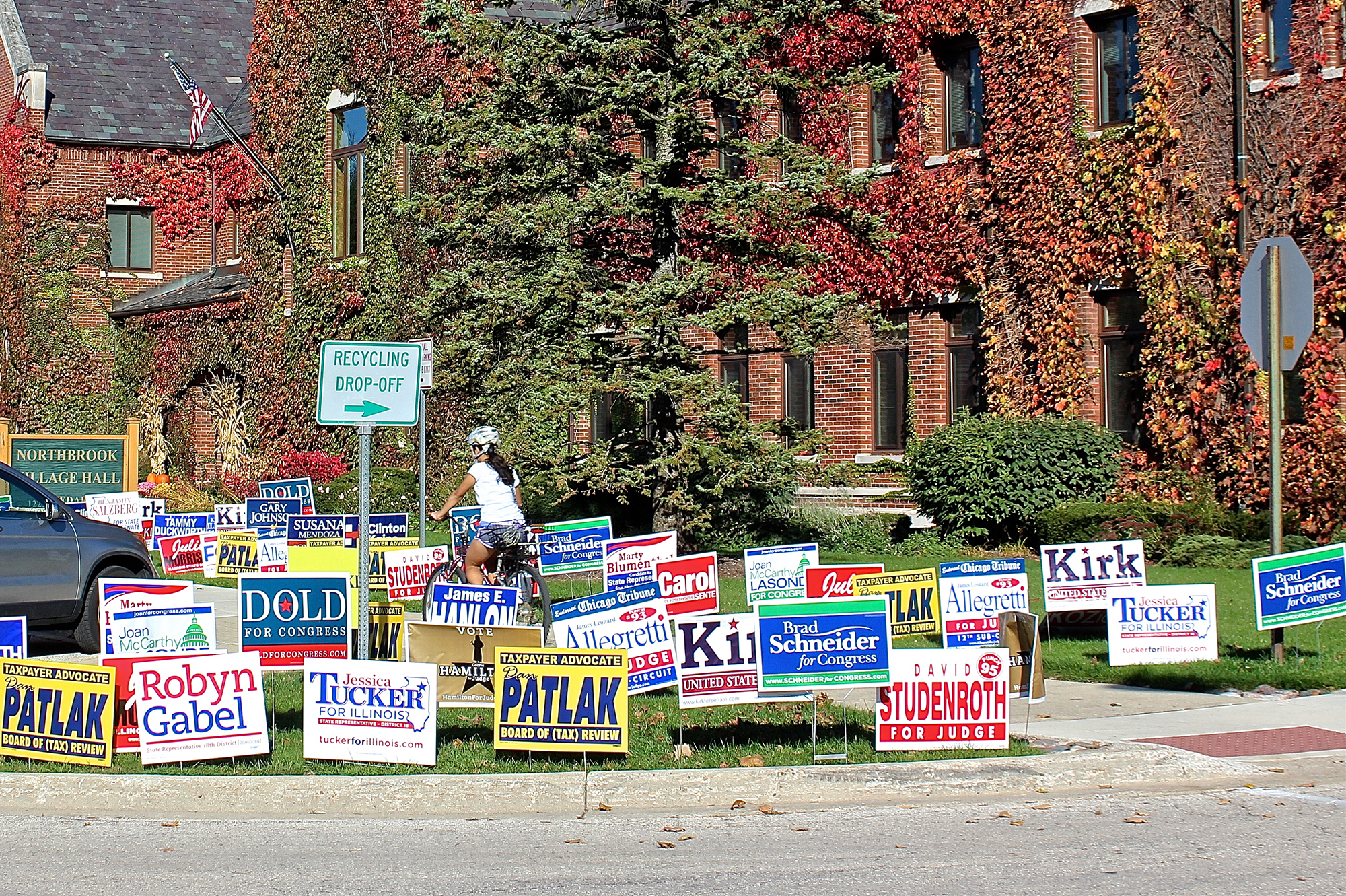 Biker riding through election political lawn signs outside polling place