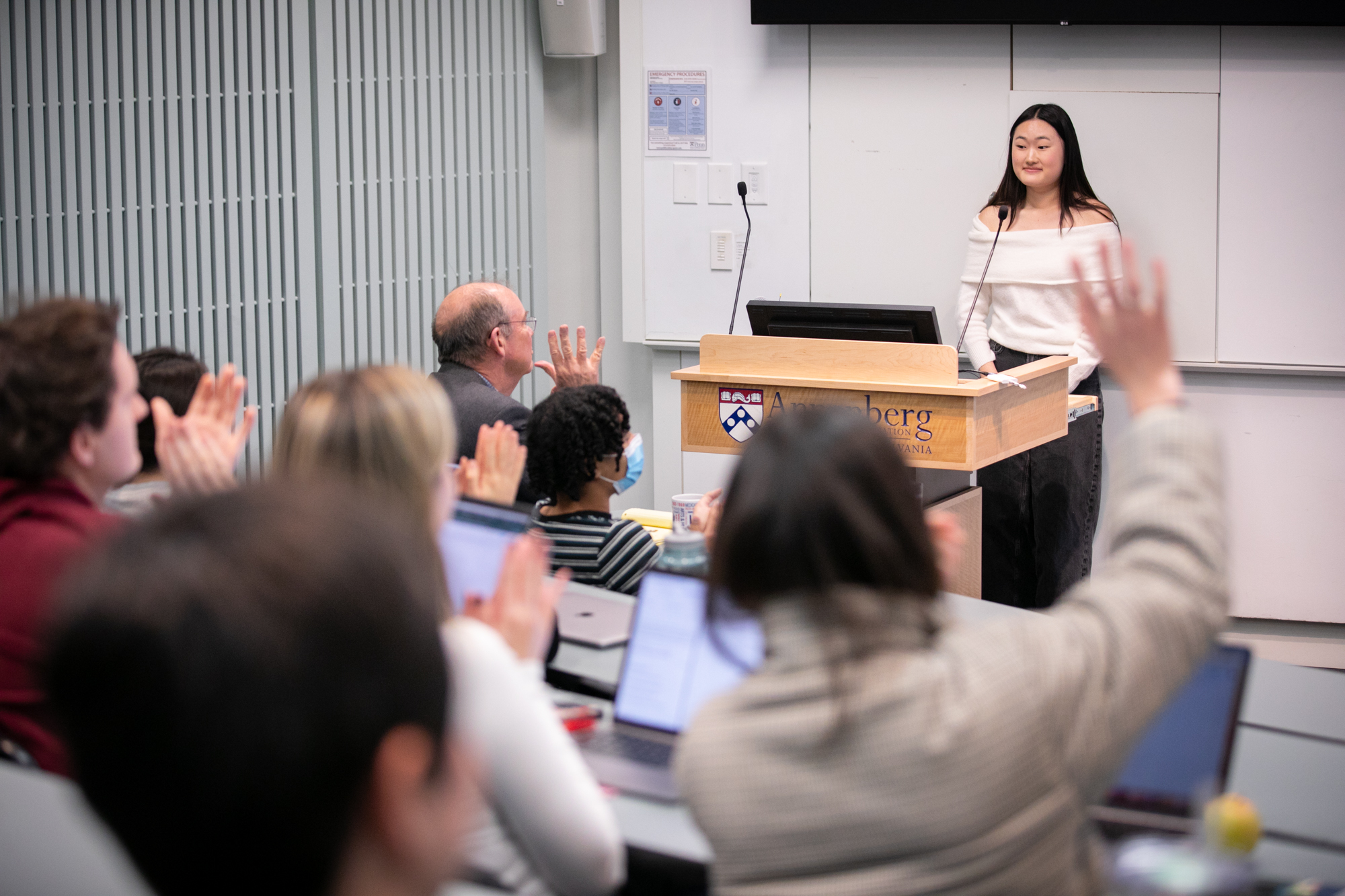 student standing at a podium speaking to a class