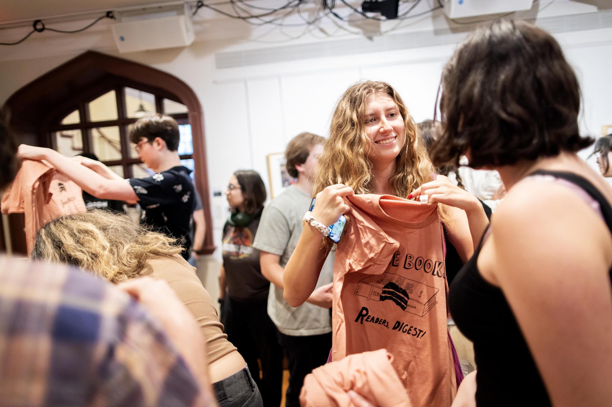 student holding up t-shirt that says edible books