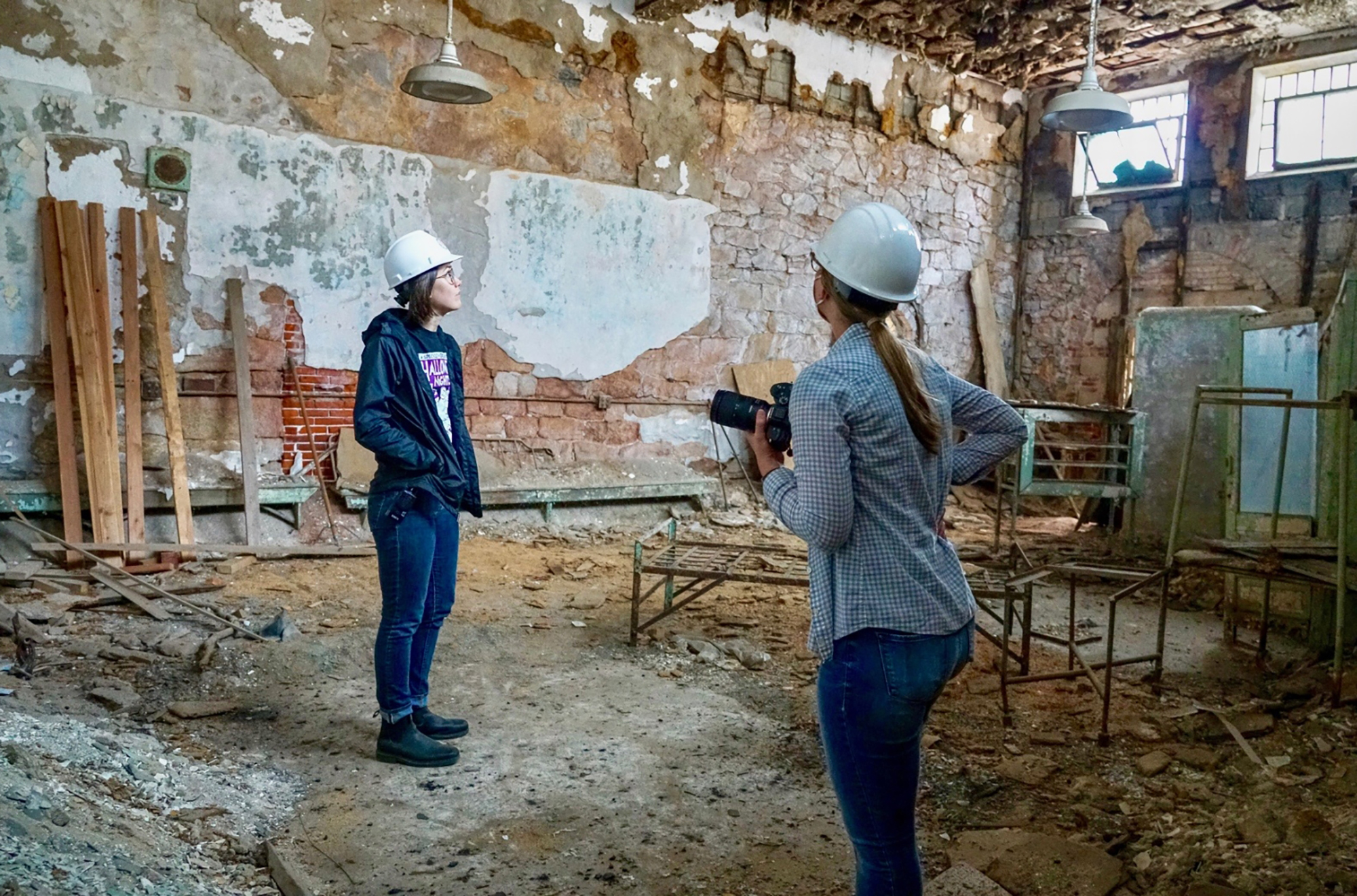 Liz Trumbull and Cameron Moon in the hospital ward of Eastern State Penitentiary, wearing hard hats.