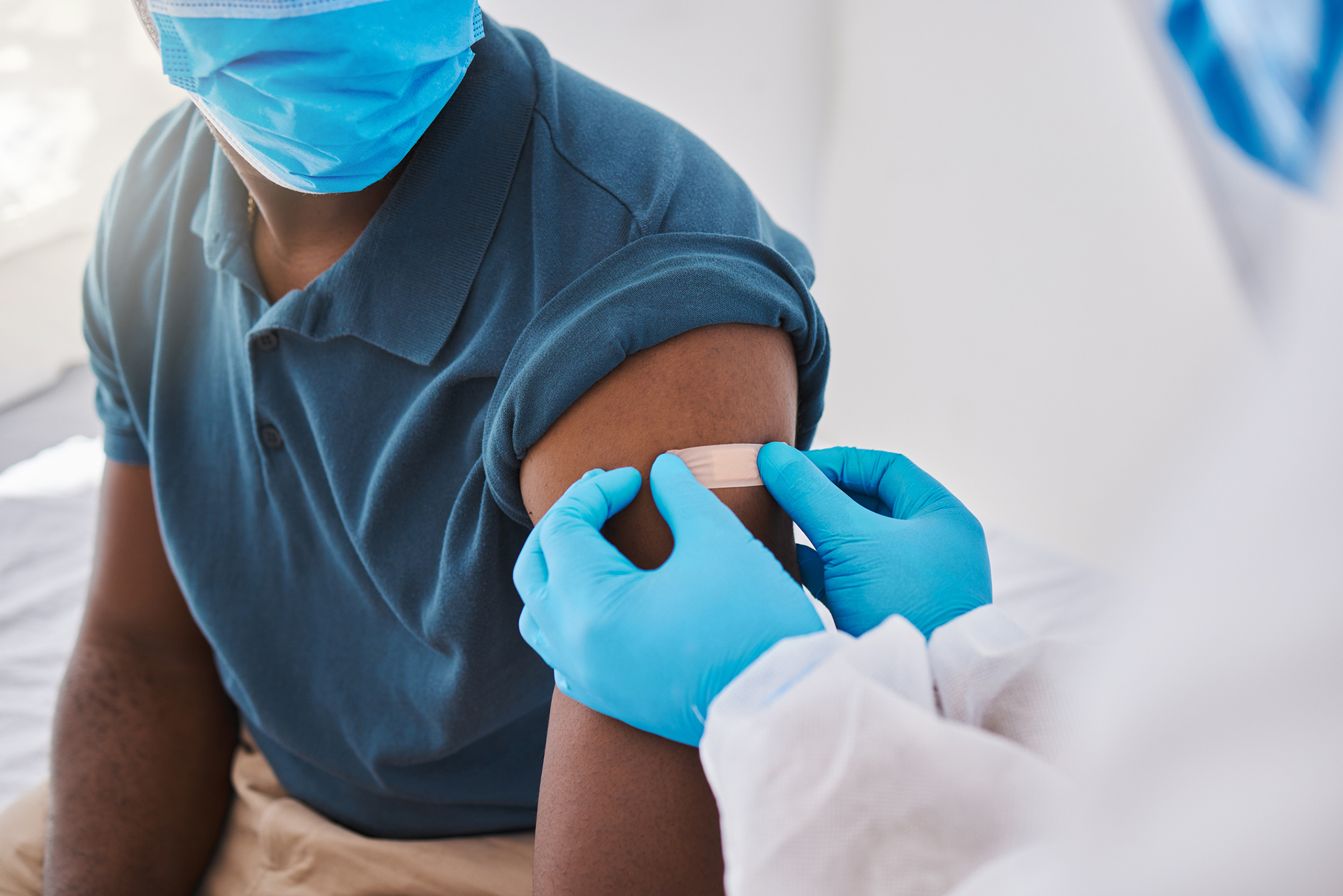 A medical professional applies a bandage to a person’s shoulder after receiving a vaccine.