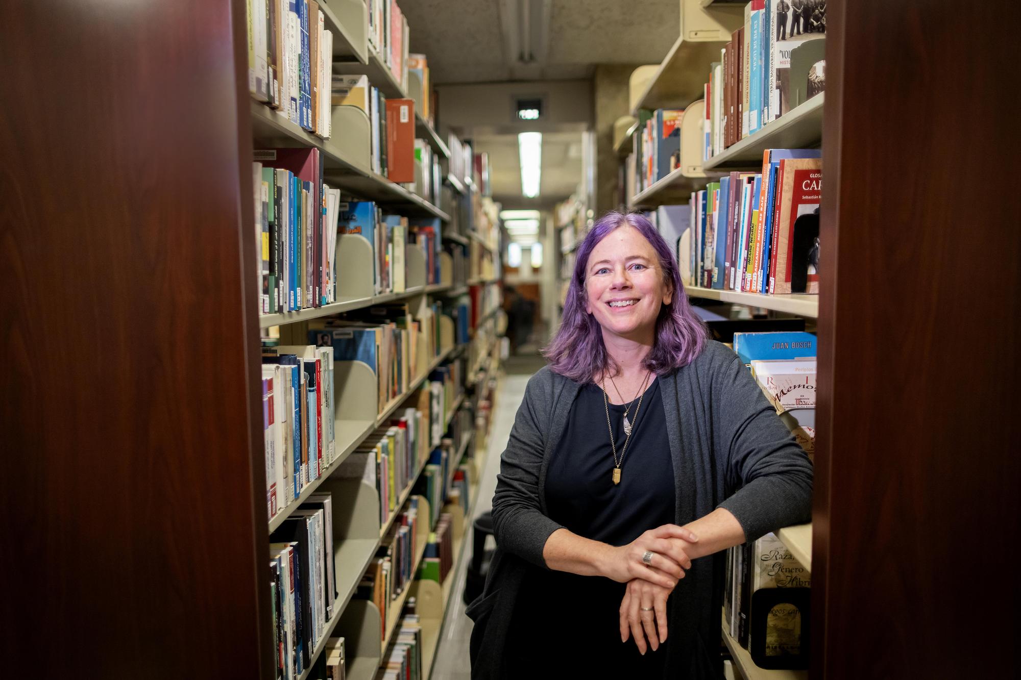 Brie Gettleson leans her elbow on a shelf in the library stacks