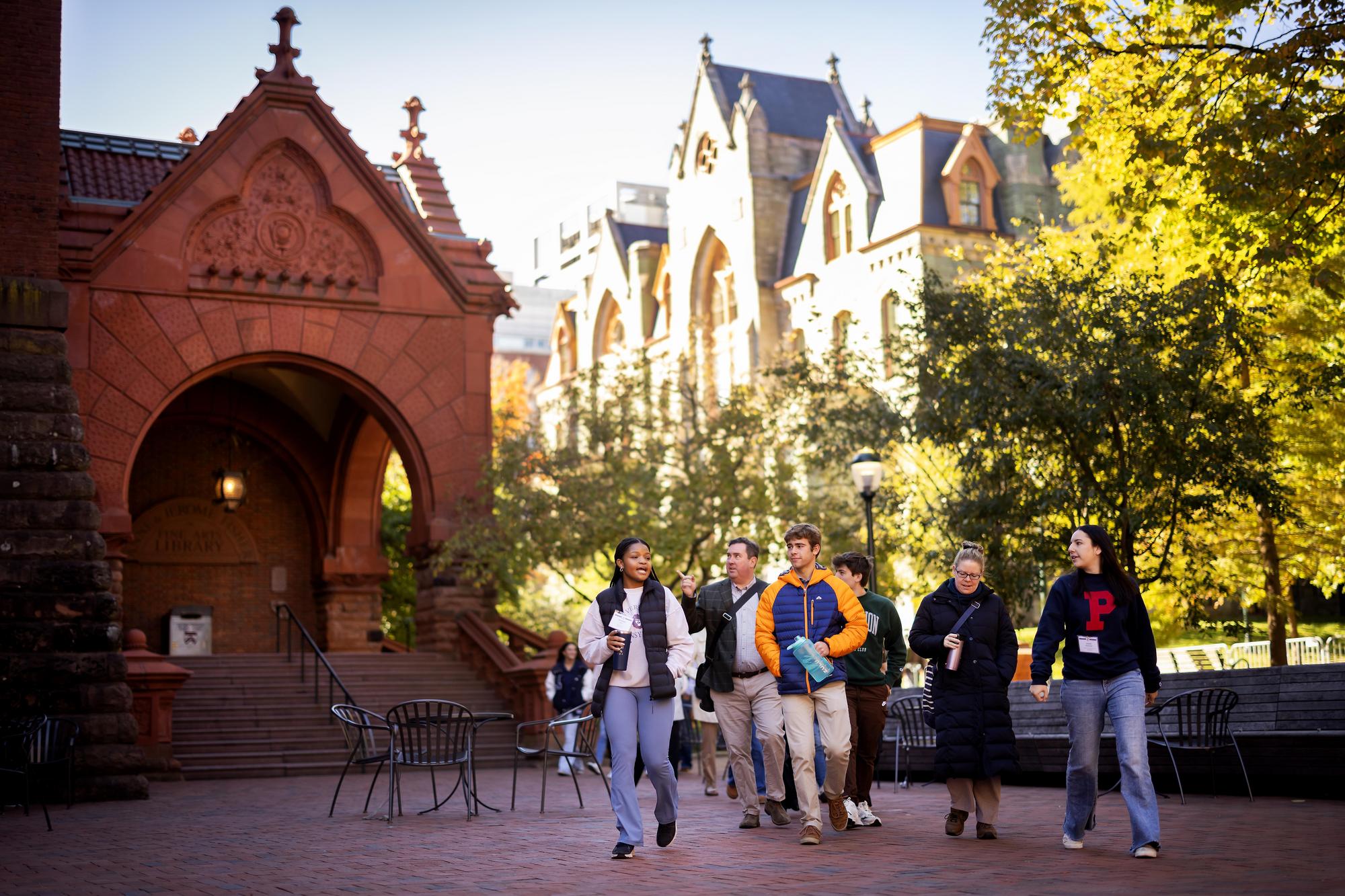 A tour guide leading a group of people outside Fisher Fine Arts Library.