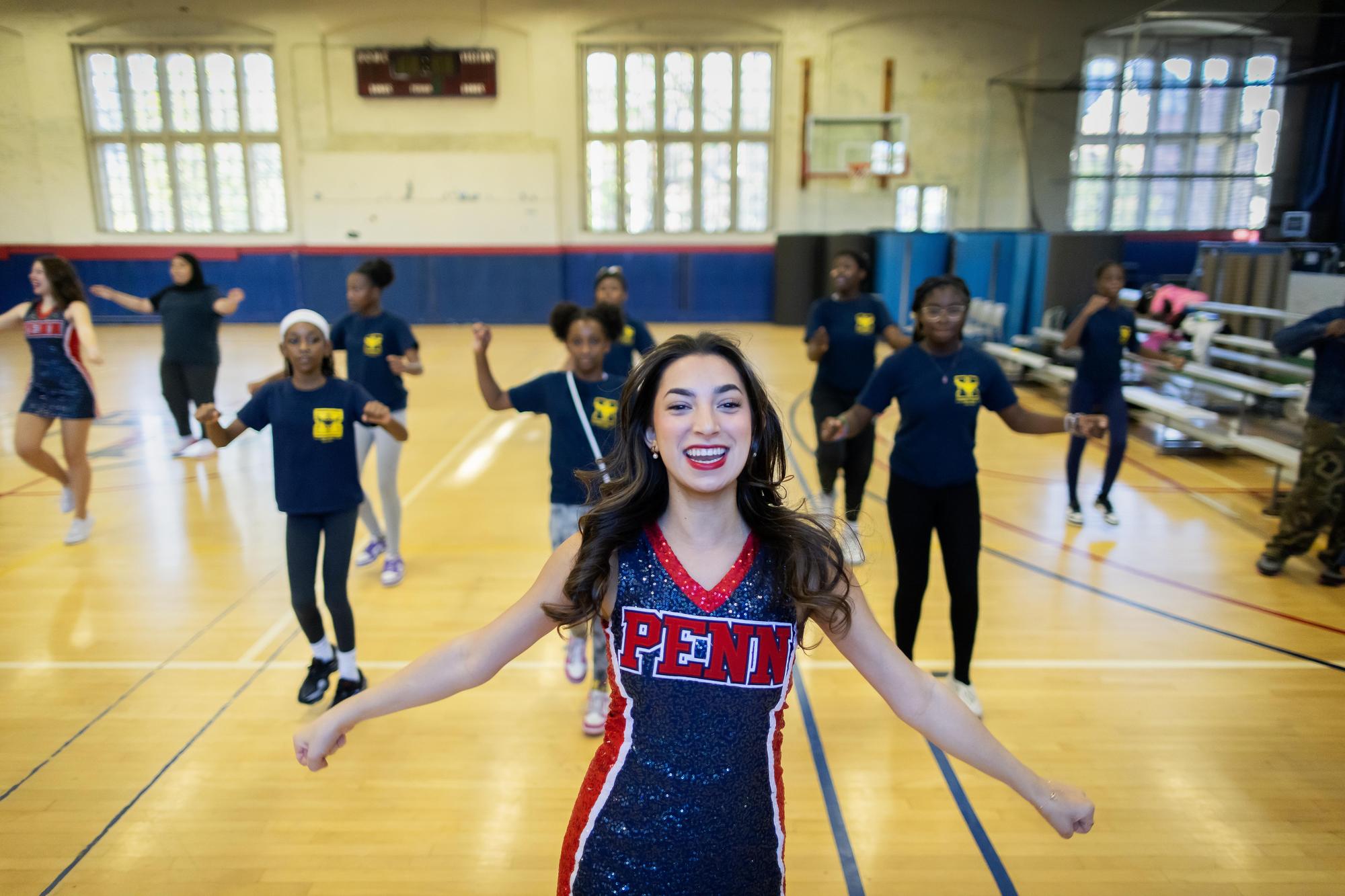 One of the Quaker Girls (wearing a uniform saying PENN) leads West Philadelphia students in dance choreography. 