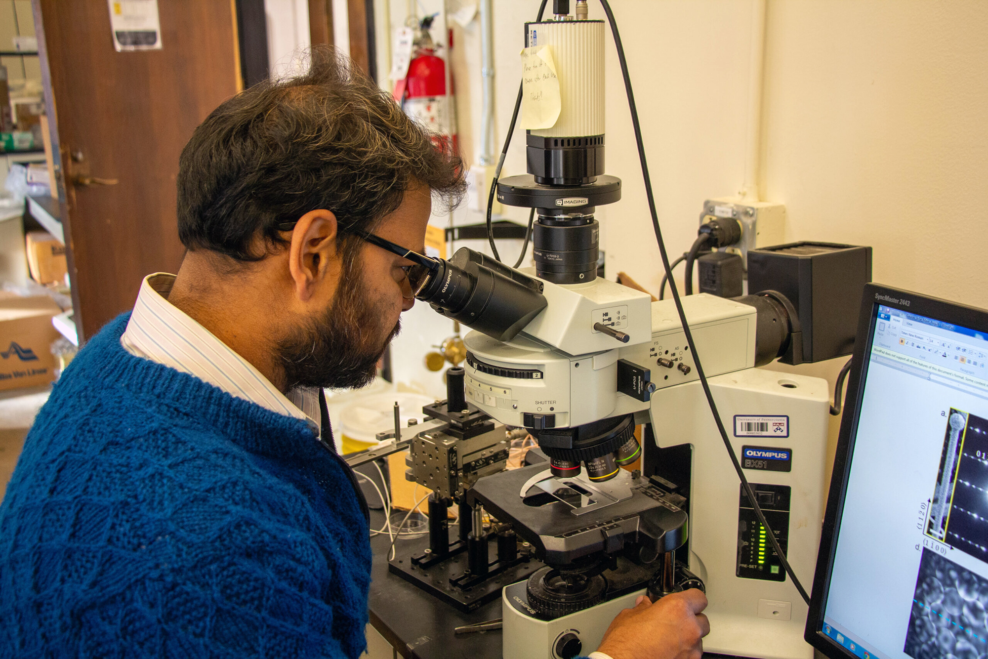 Ritesh Agarwal looks through a microscope in his lab.