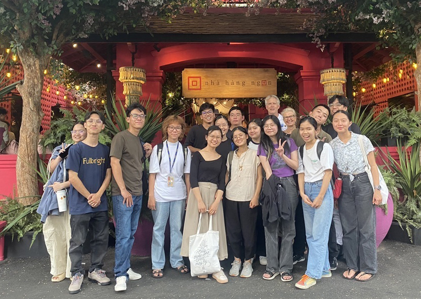 Group of students and professor pose for a photo in front of a restaurant.