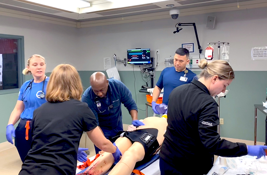 A Navy trauma team in a hospital room doing triage on a mannequin.