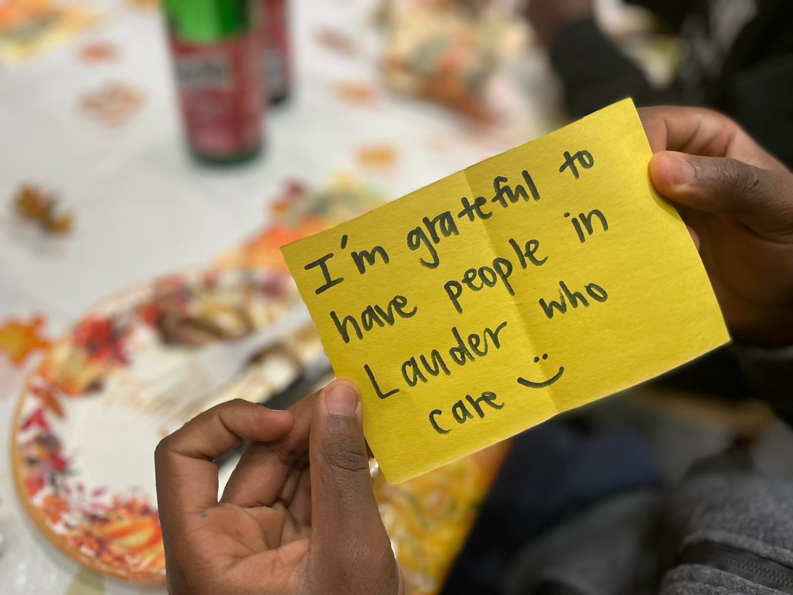 Hands holding a note that says "I'm grateful to have people in Lauder who care :)"