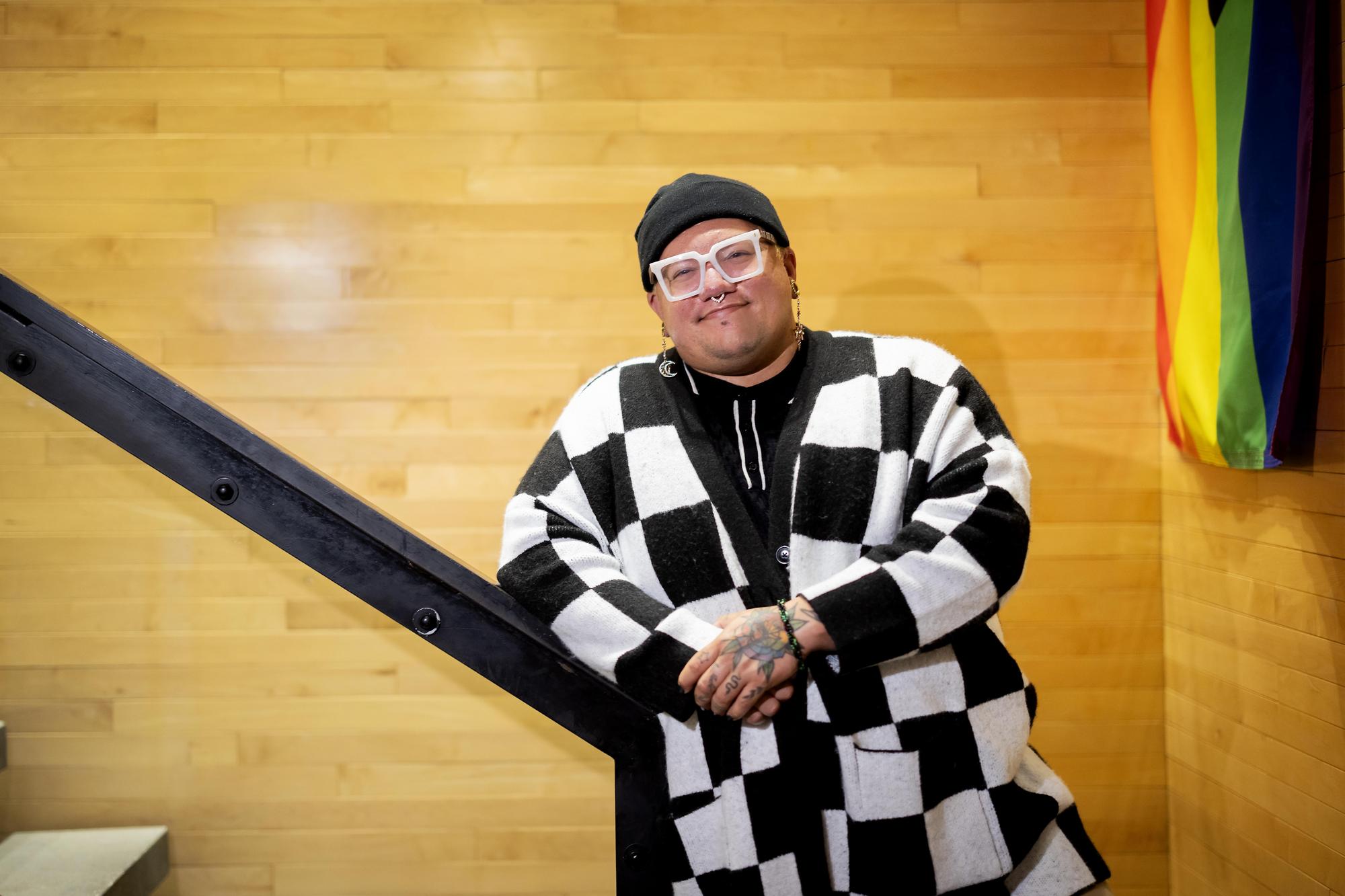 Eric Anglero stands in the hallway of the LGBT Center, a rainbow flag to their right