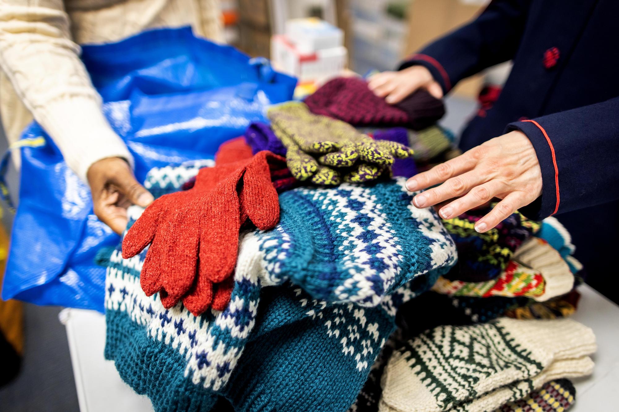 Mary Kinney and a pile of donated sweater and gloves she knit.