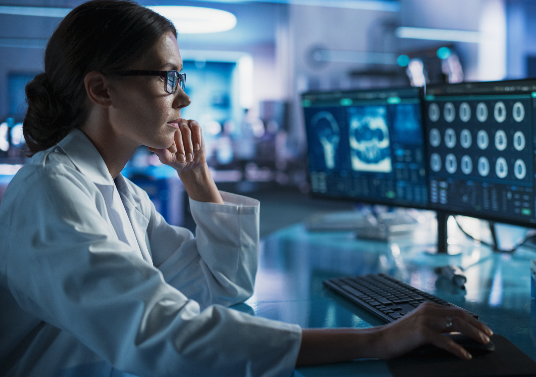 A researcher looking at brain scans on a computer in a lab.