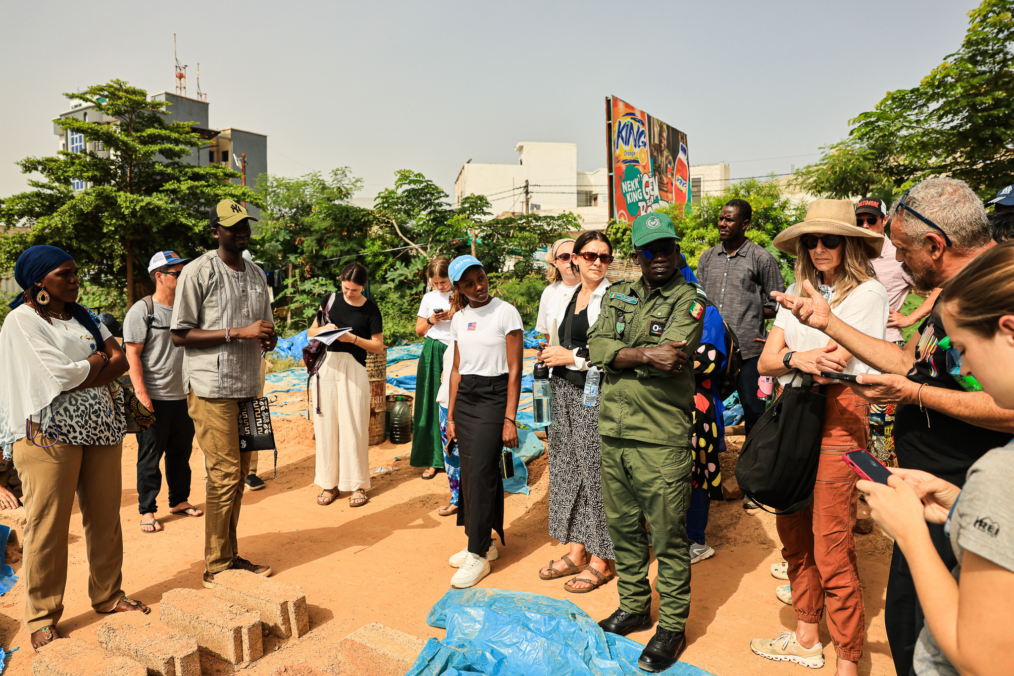 A group of people, including uniformed personnel and researchers, gathers outdoors in a discussion.