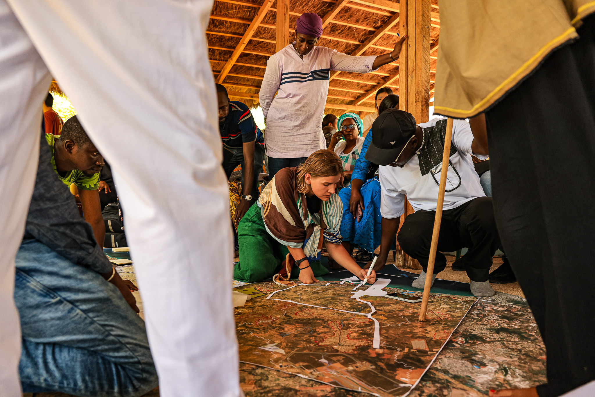 People gather around a large map placed on the floor.  