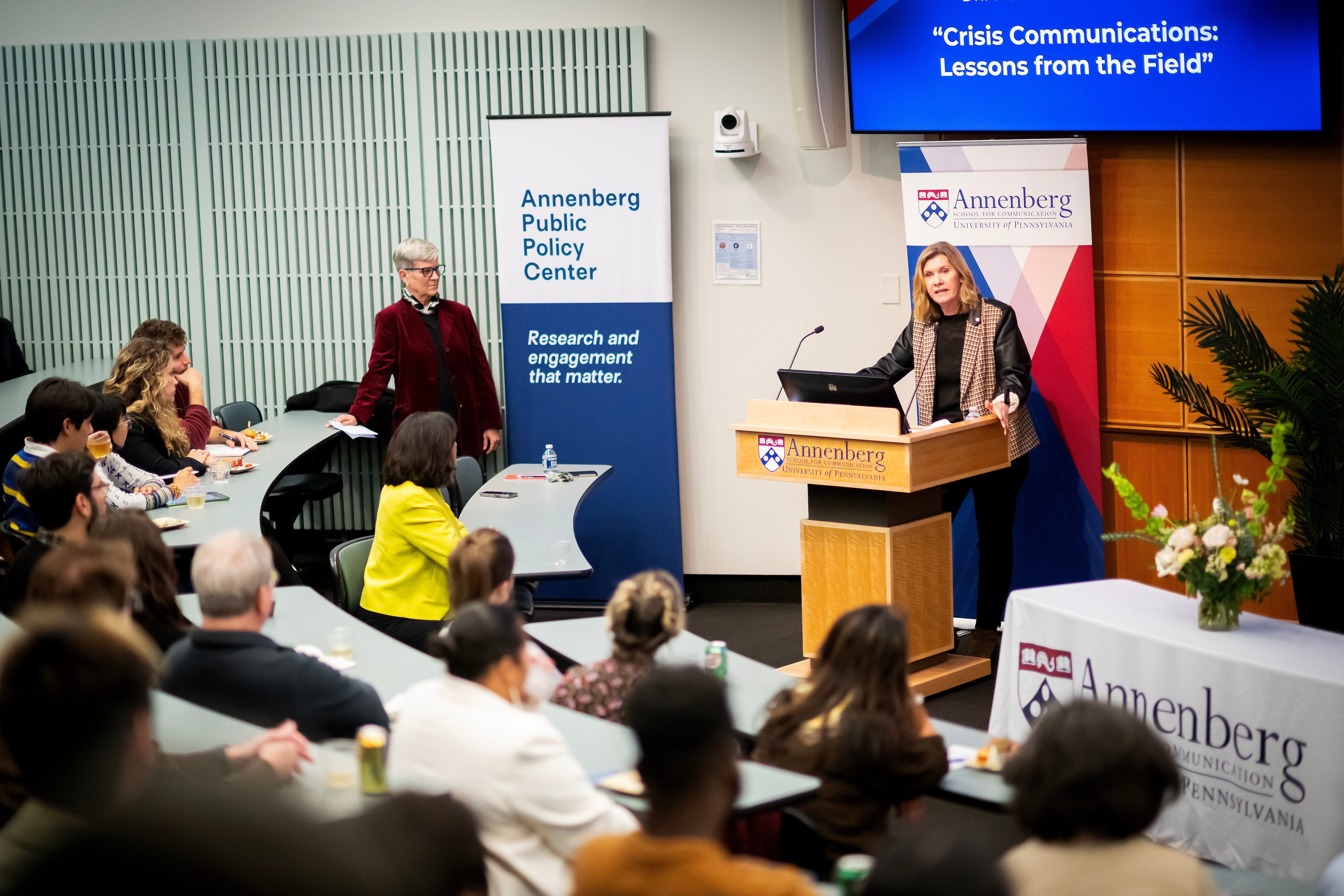 Sarah Banet-Weiser addresses a room of people while speaking at a podium.