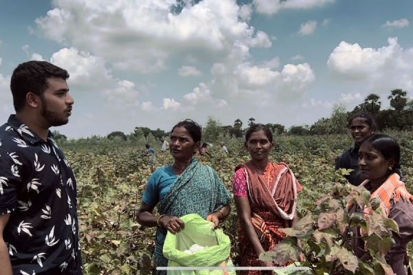 Gobhanu Korisepati standing in a field in India speaking with four women.