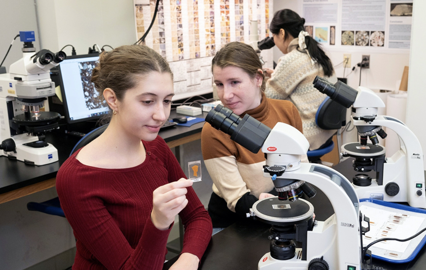 Two students who look at slides under a microscope in a laboratory.