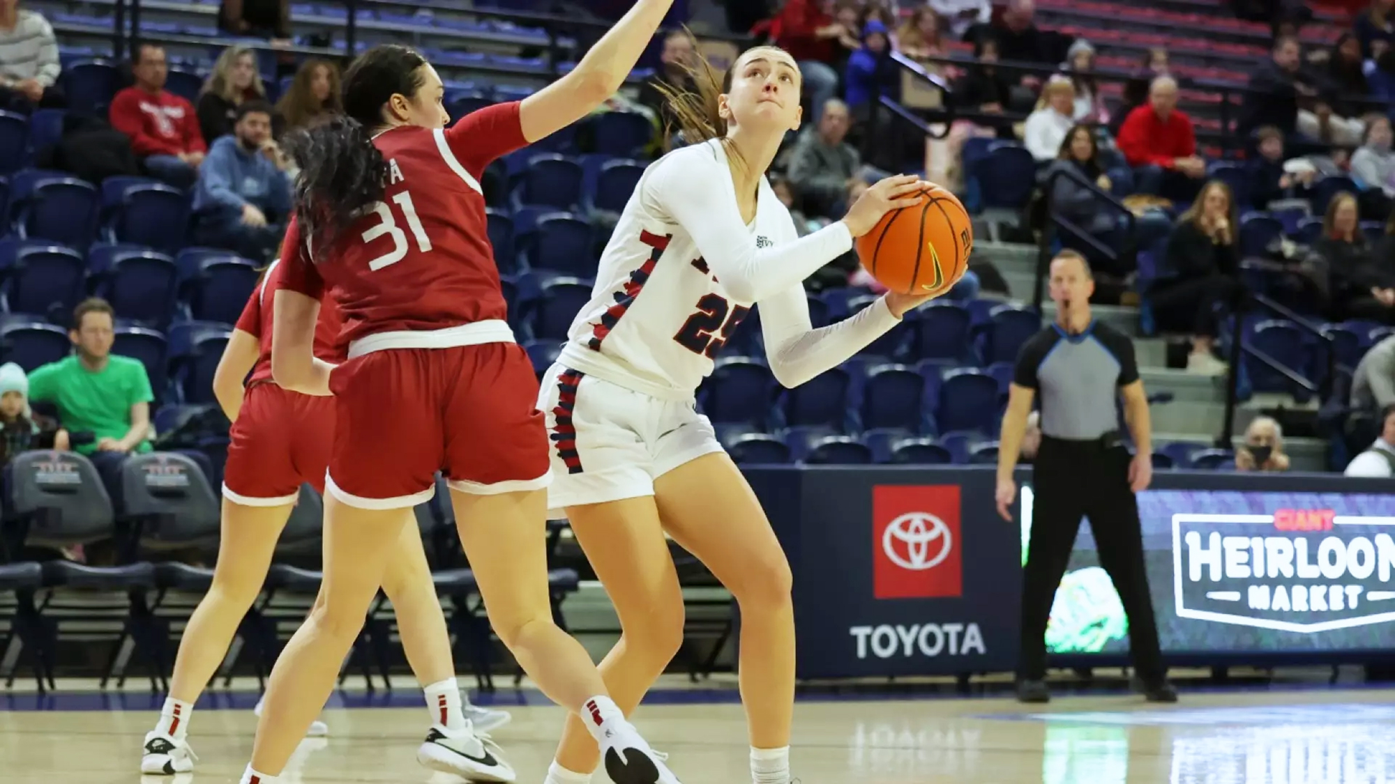 Katie Collins makes a move with the ball while guarded by two defenders.