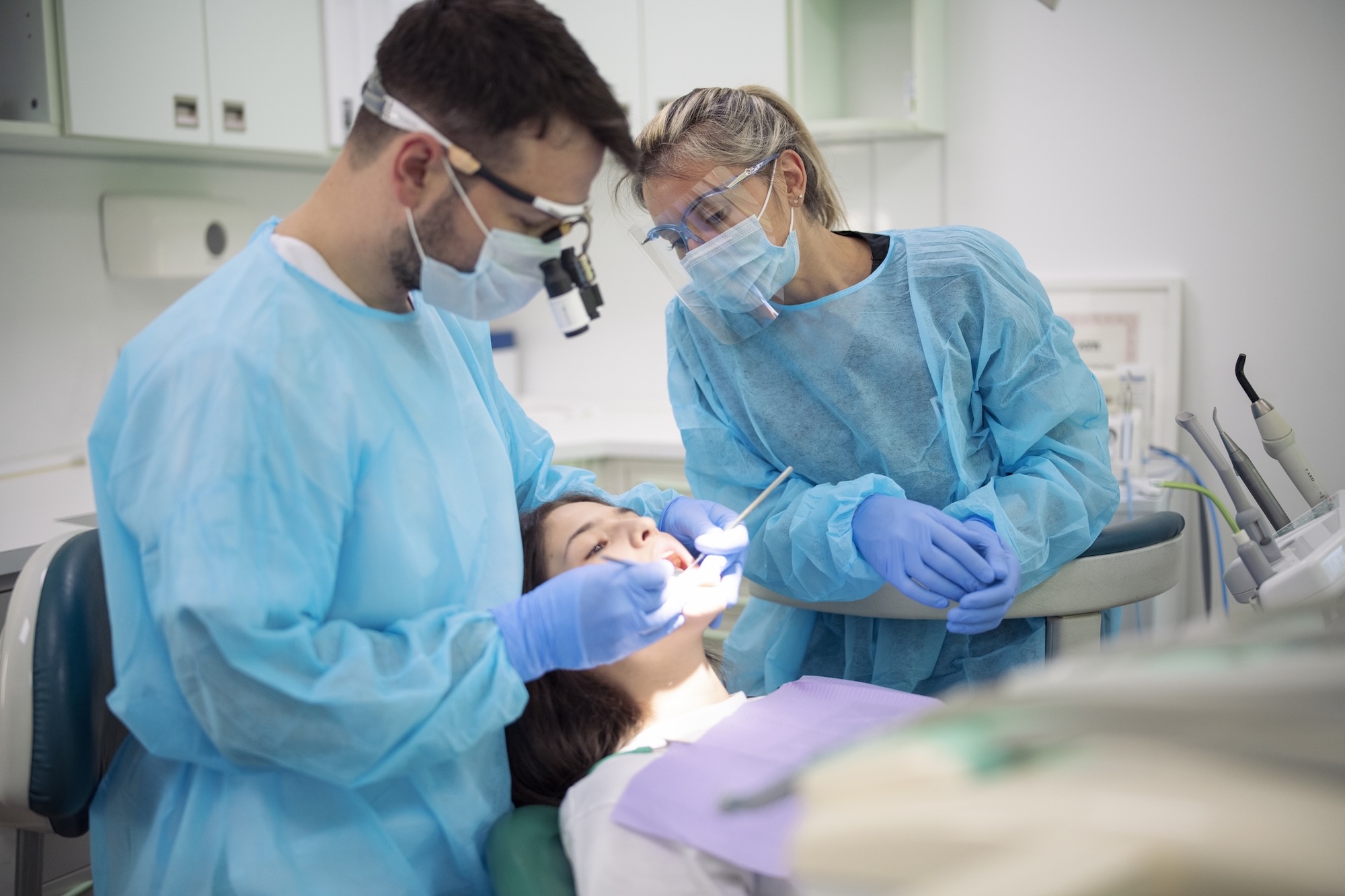 Dentist and assistant working on young female patient in dental clinic.