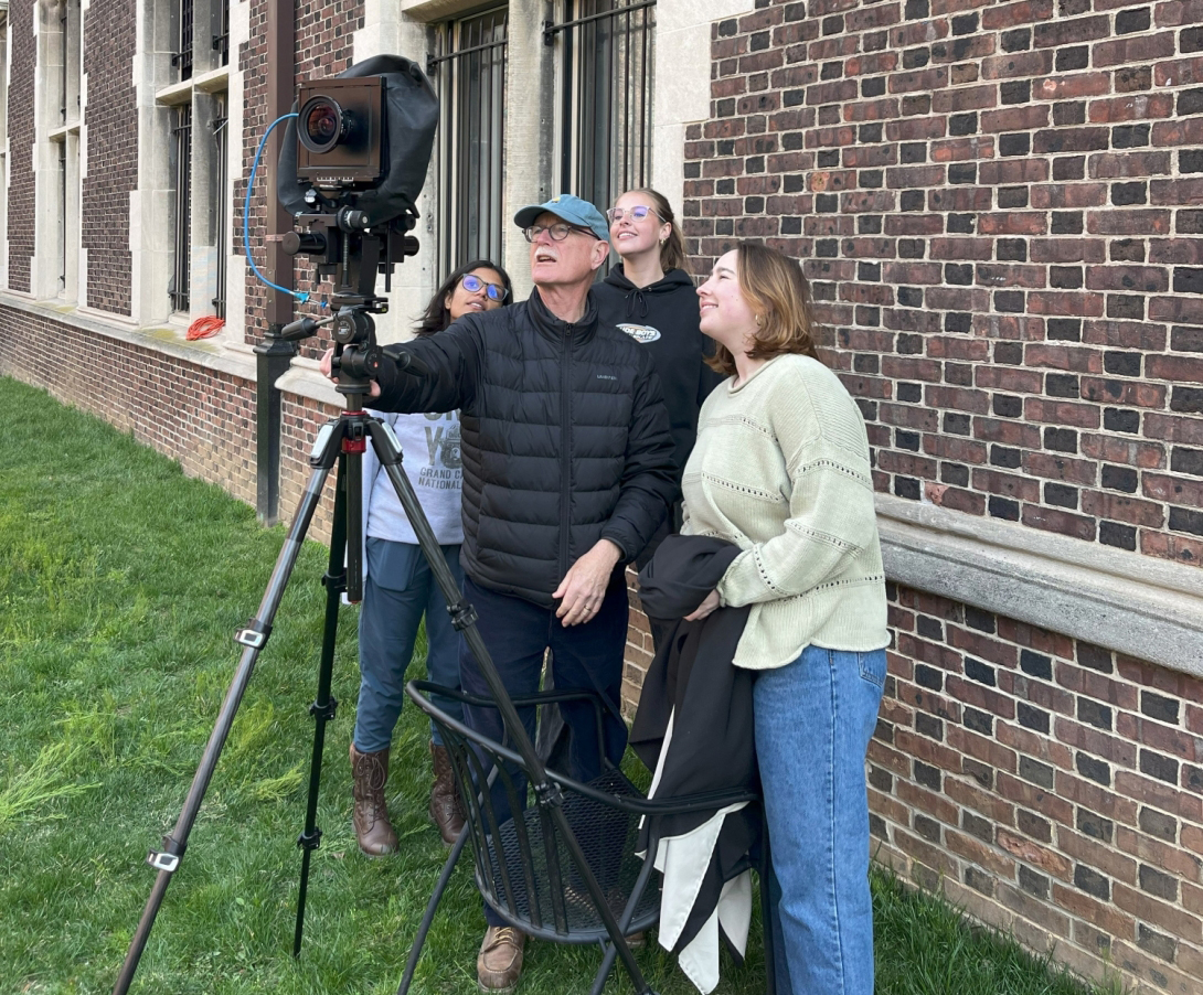 Elliot Joseph and three Weitzman students look through a large-format camera on Penn’s campus.