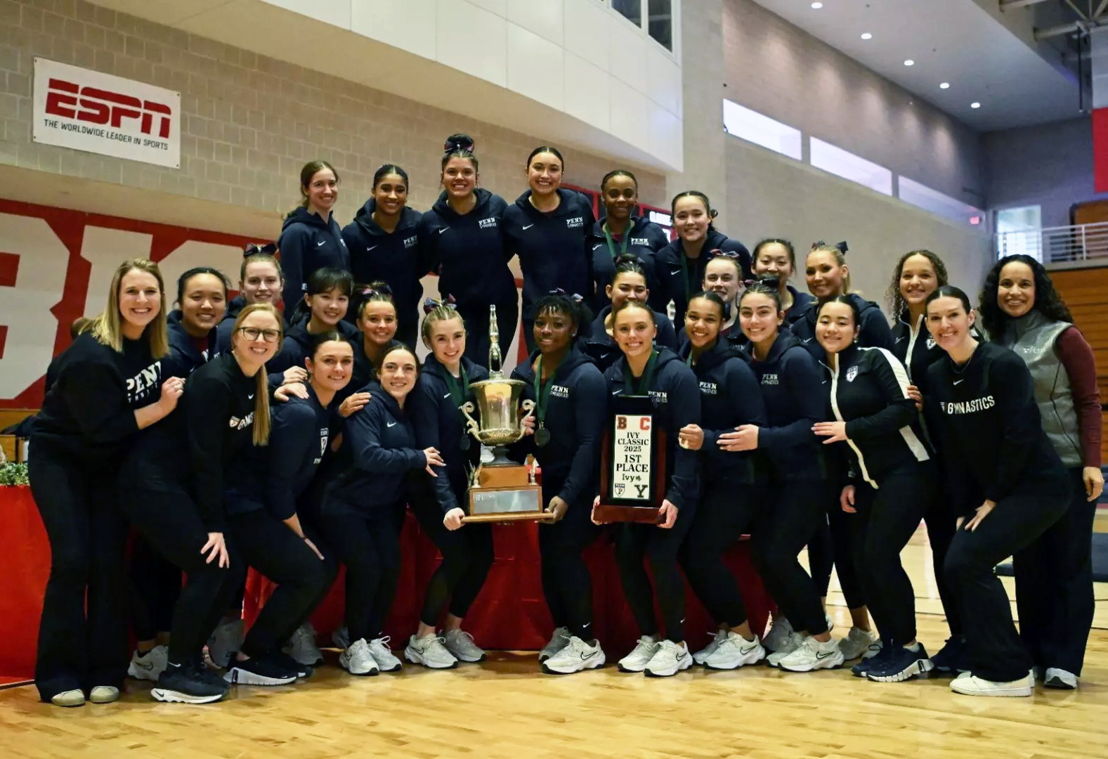 Penn’s gymnastics team holding a trophy.