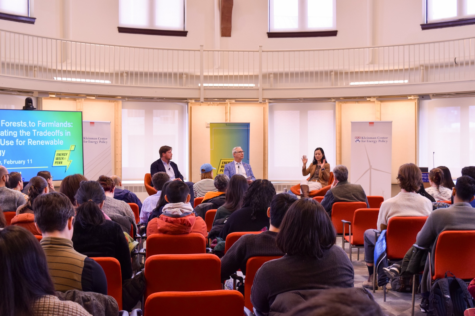 Three speakers in front of audience in Kleinman Center Energy Forum.