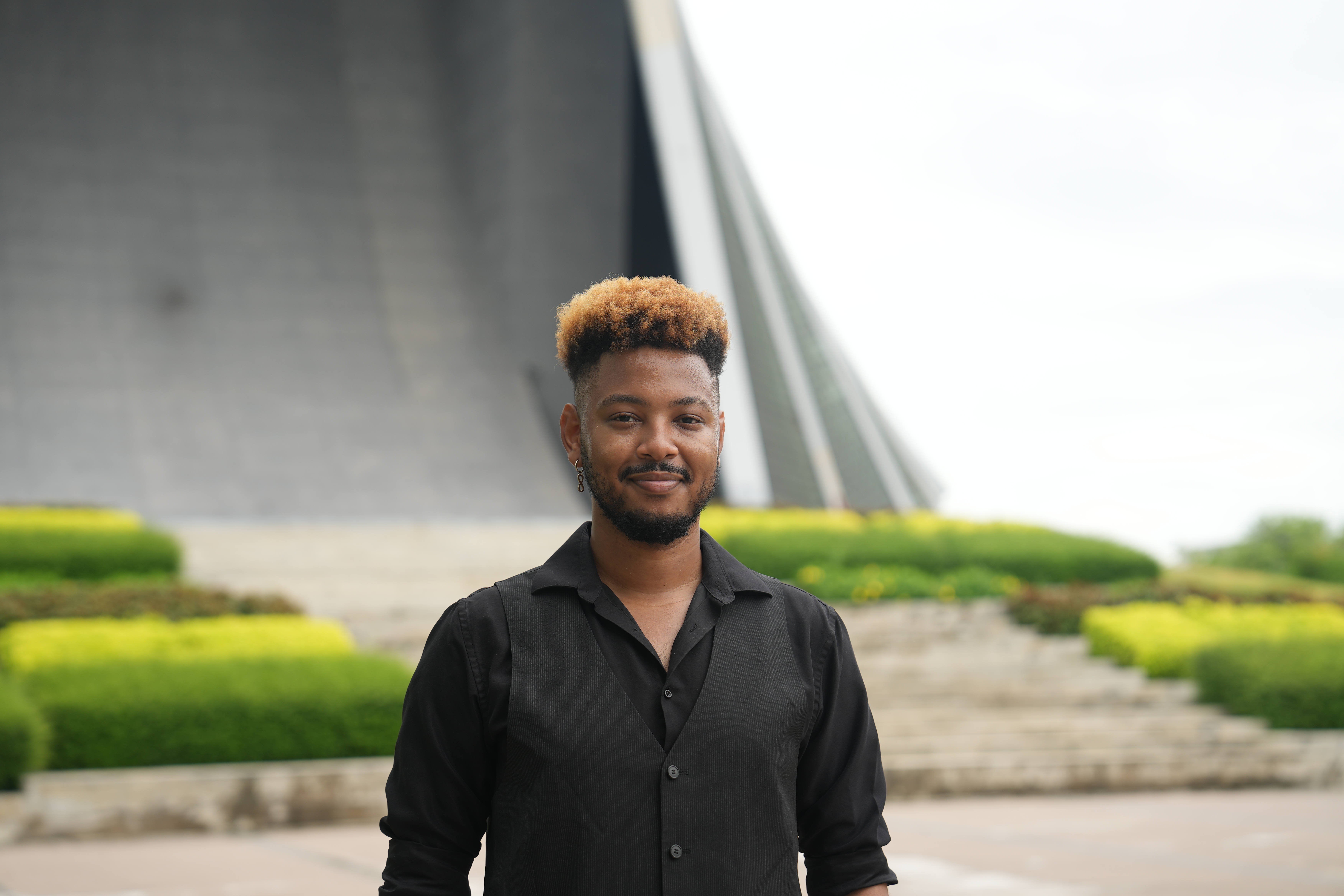 Timethius Terrell standing upright in a bright outdoor setting, while smiling and facing forward.