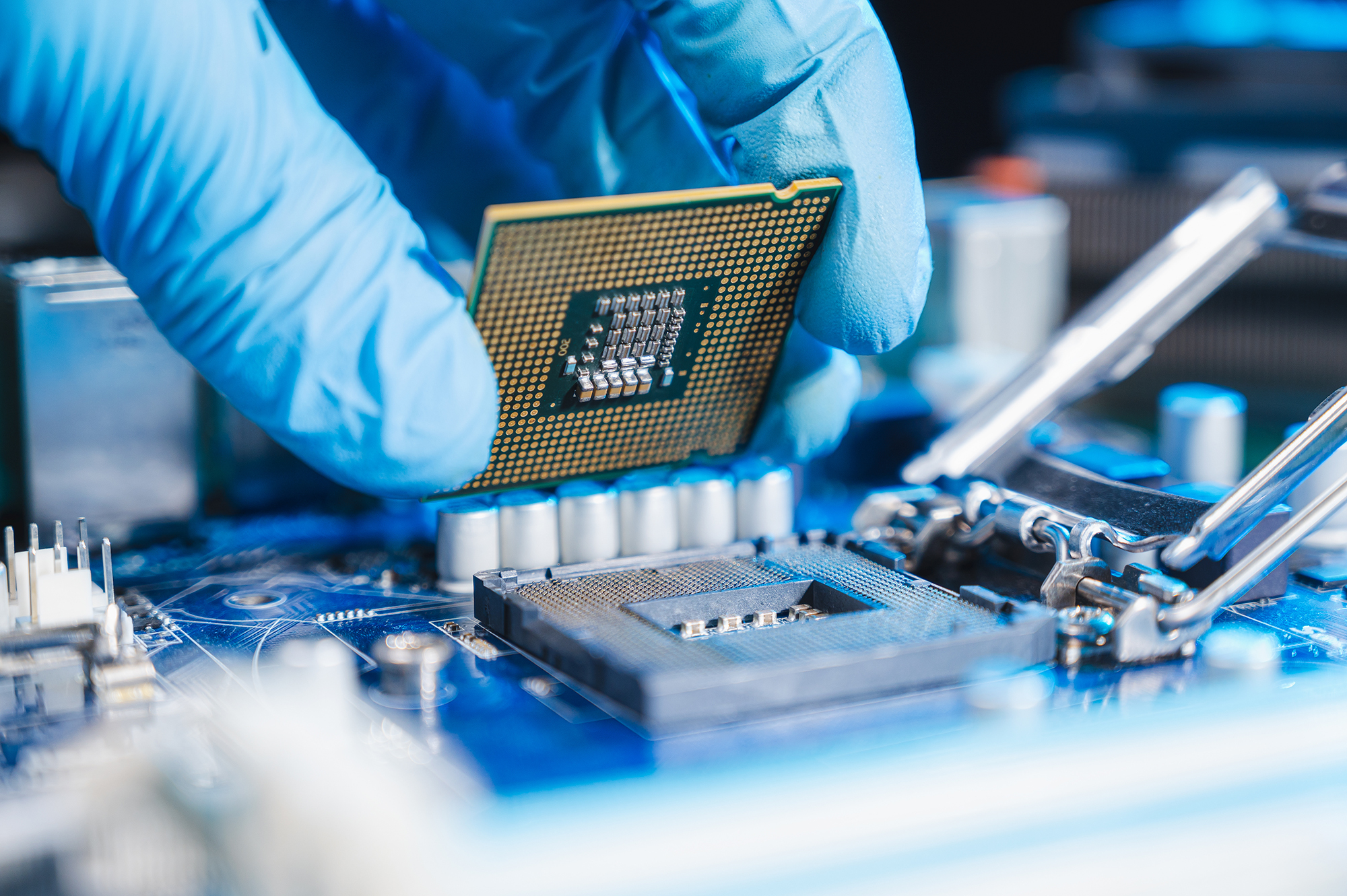 A computer chip being placed by a rubber-gloved hand.