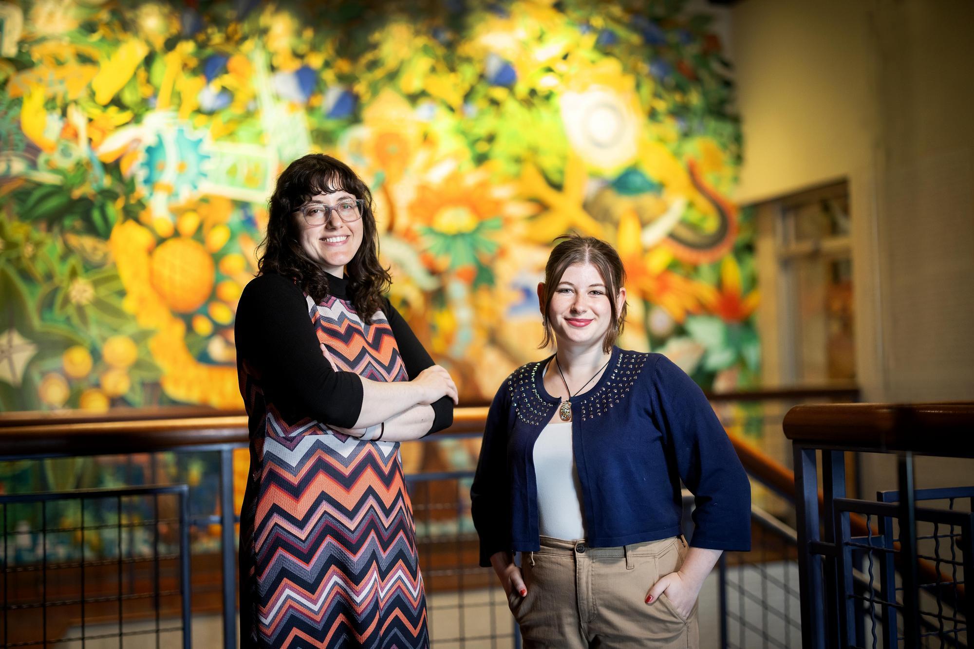 Lucy Briggs and Luiza Sulea standing in front of a colorful mural