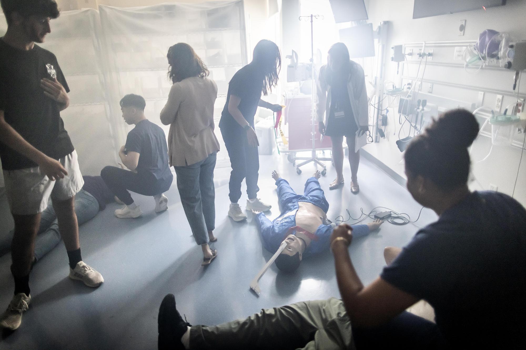 Nursing students, actors, and mannekin in a smoke-filled simulation room.
