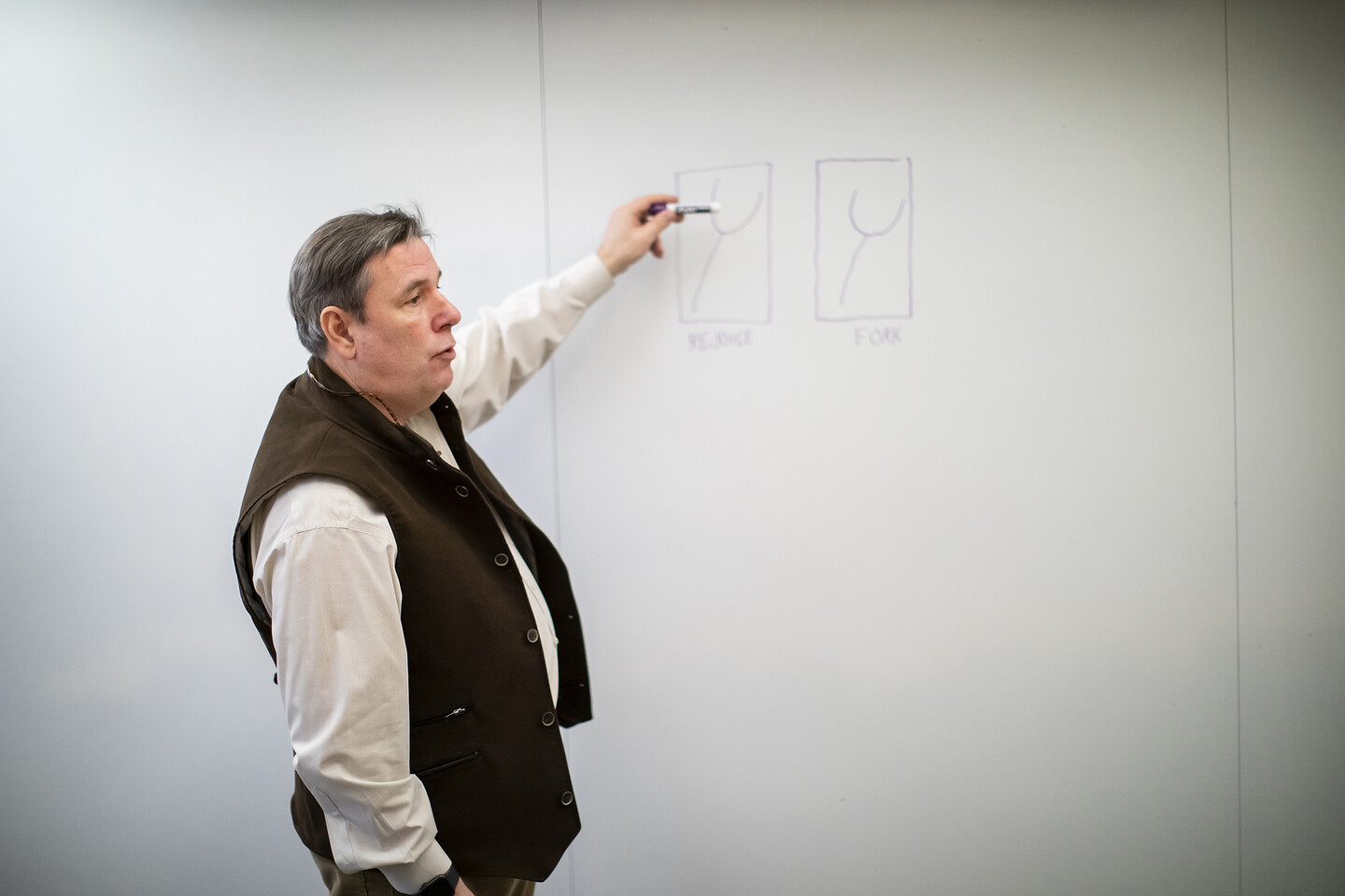 Robert Berry at a white board with two images showing a fork, one juxtaposed with text "Rejoice" and another with "Fork"