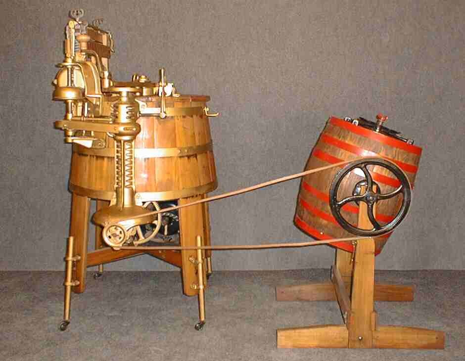 An old-fashioned washing machine, which looks like two wooden barrels on legs, next to each other and connected by large wiring.