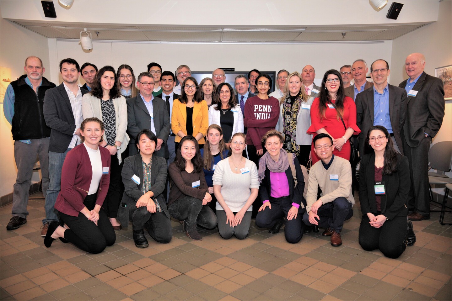A group of three rows of people wearing nametags poses for a photo.