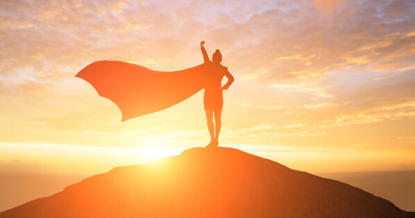 a silhouette of a woman with a cape standing on top of a hill