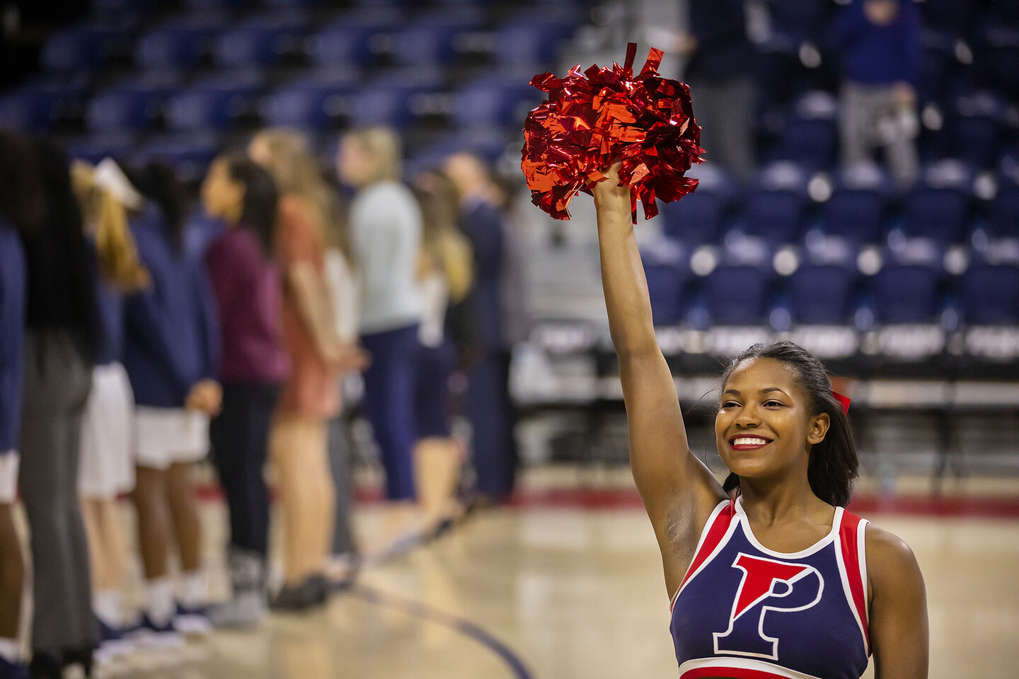Maya Moore raises a pom-pom in her right hand at a basketball game.