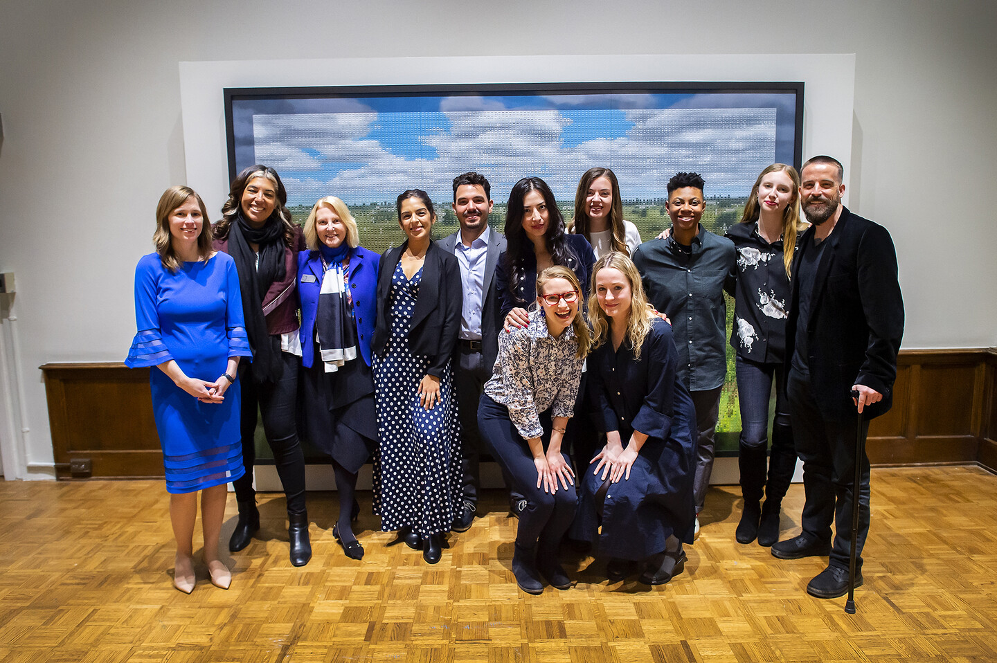 Artist and professor and curator and students gathered in front of a painting.