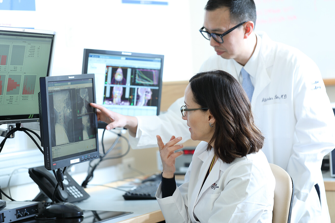 Patricia Corby and Alexander Lin view a radiograph of a person's head and neck on a computer screen